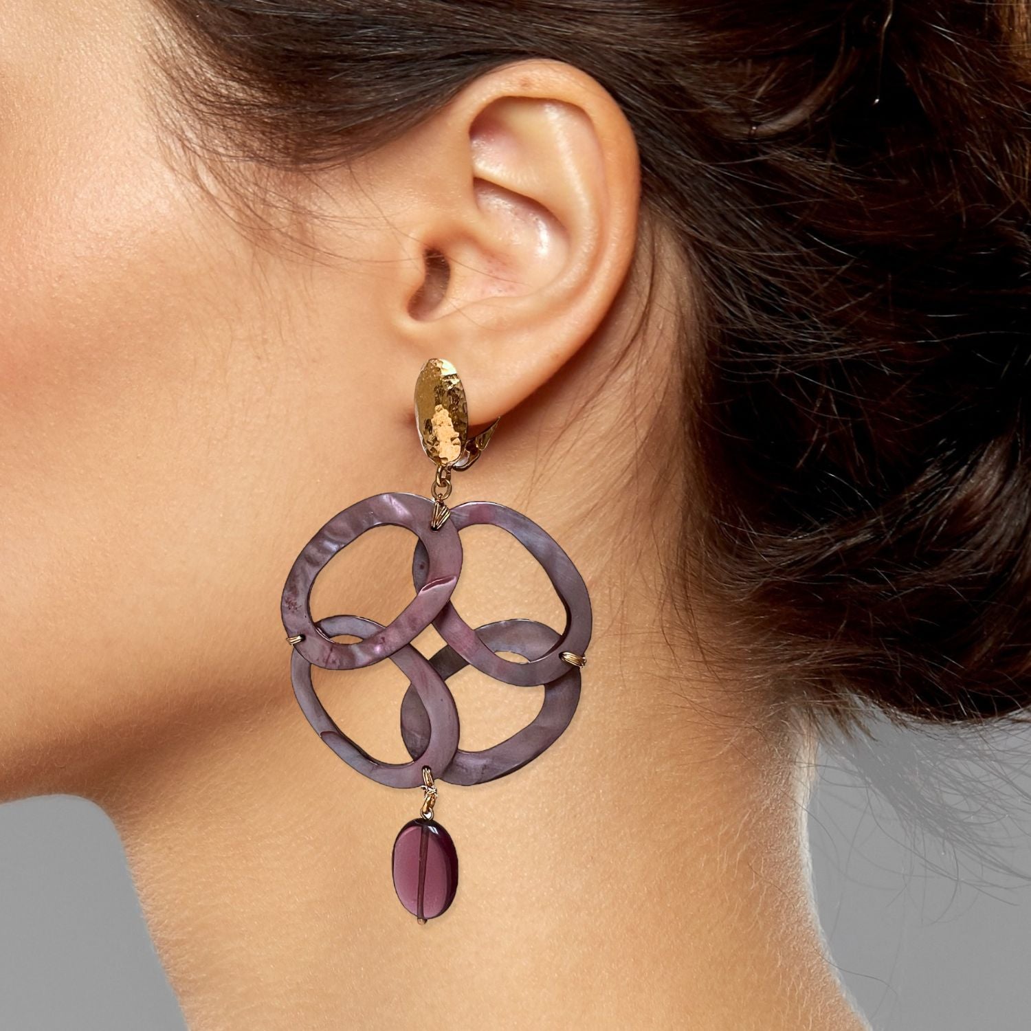 The Oriental Legend Clip On Earrings by JAREDJAMIN Jewelry Online feature hammered 18K gold plated studs, three interlocking purple resin ovals, and a dangling round bead for a bold, elegant look.