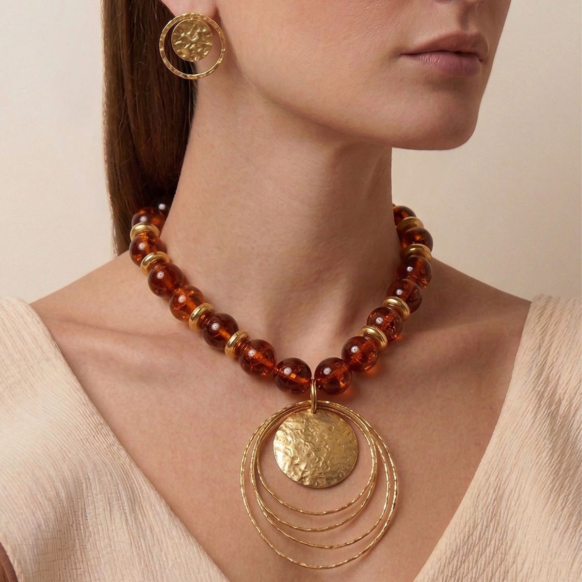 modelo usando the 18.5-inch Peacock Dawn llamativo colgante in Amber, showing the high-impact placement of the large oro architectural colgante at the collarbone against a neutral outfit.