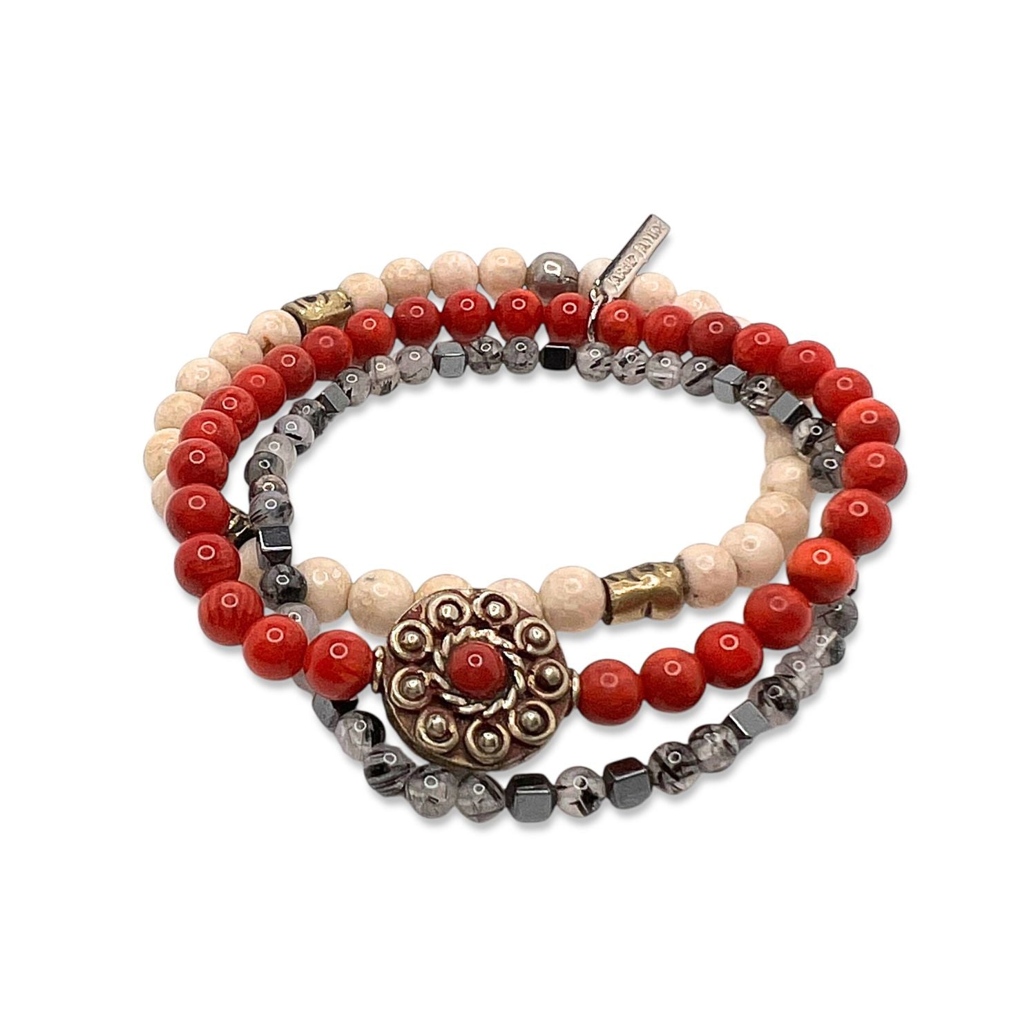 The Red Barron Bracelet Set by JAREDJAMIN Jewelry Online features coiled coral, beige, and metallic gray beads with a silver floral medallion accented in red and metallics for a layered, bohemian style.
