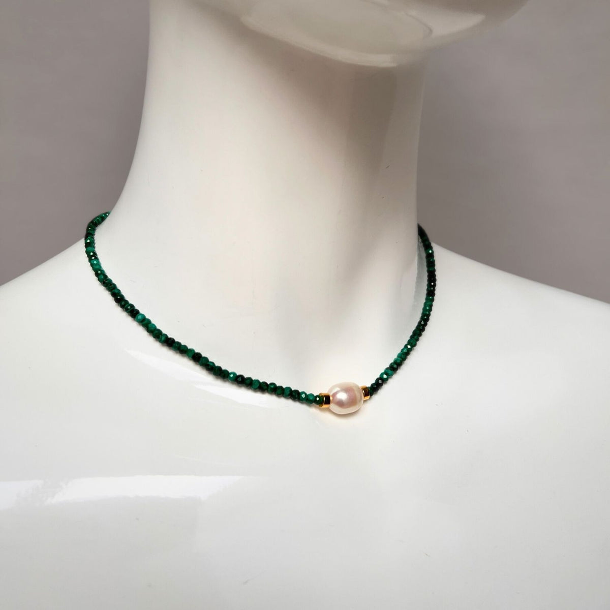 Un mannequin showcases the Rowan collier Malachite par JAREDJAMIN Bijoux en Ligne, avec small dark green malachite beads et a central round freshwater perle avec or-colored accents, set against a plain background.