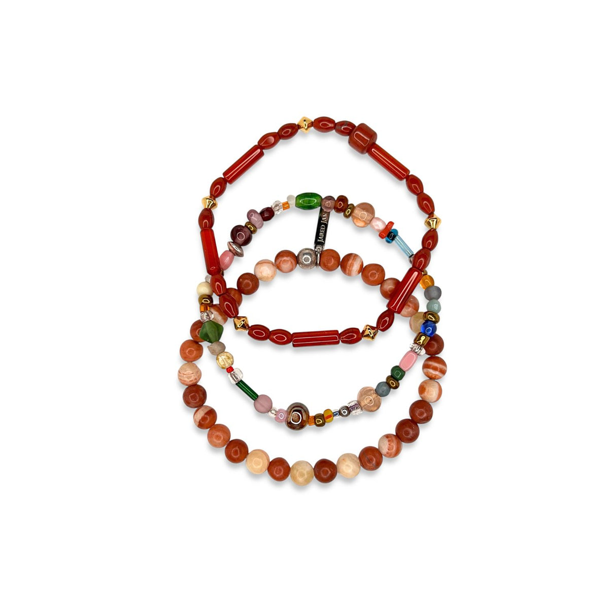 The Scorpion King Bracelet Set by JAREDJAMIN Jewelry Online features three beaded bracelets: red jasper with gold accents, colorful agate beads, and marbled brown round beads, each with distinct patterns on a white background.