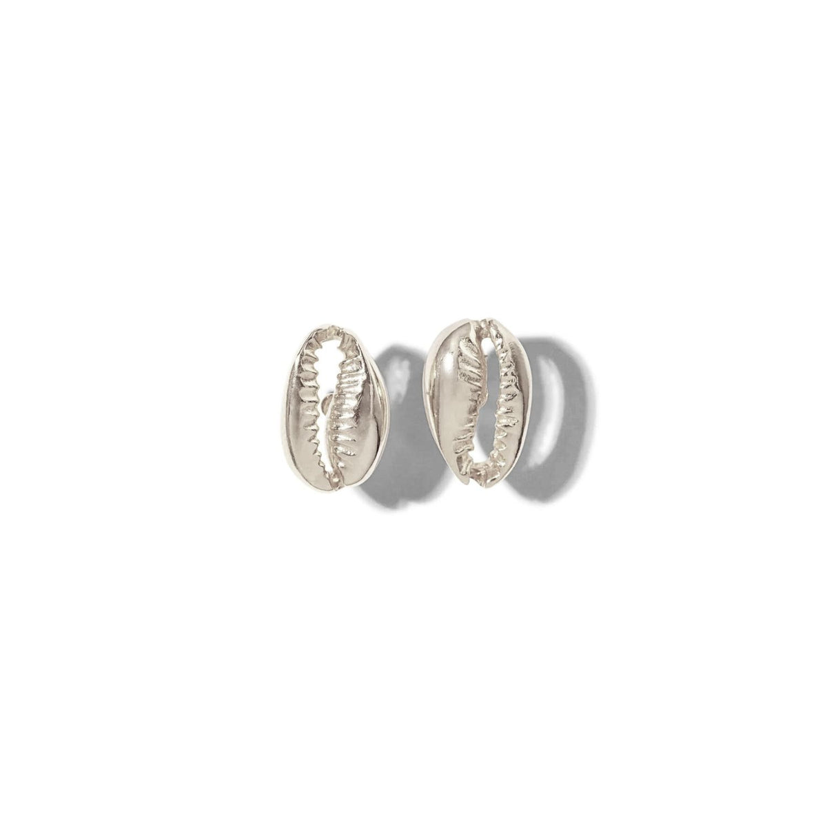 Los JAREDJAMIN Joyería Online plata Cowrie pendiente de botón Post pendientes, inspirado en cowrie shells, are exhibido sobre a fondo blanco. Los ridged center details create soft shadows that highlight their smooth, pulido finish y coastal dije.