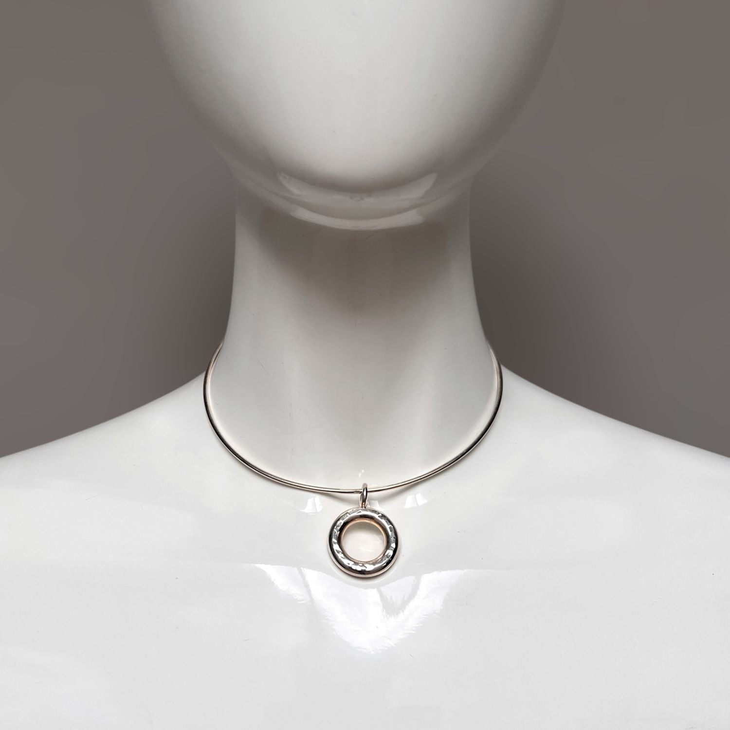 The Silver Doughnut Pendant Collar Necklace by JAREDJAMIN Jewelry Online is a minimalist, modern silver choker with an adjustable lobster clasp and a central textured doughnut pendant in a shiny finish.