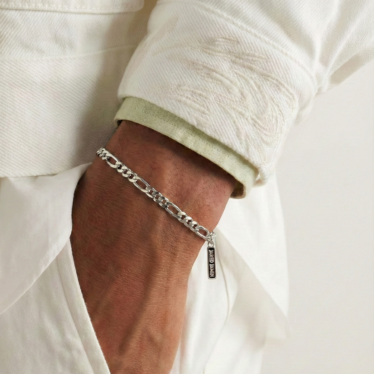 Someone wearing the plata Finley-Figaro cadena pulsera de JAREDJAMIN Joyería Online.