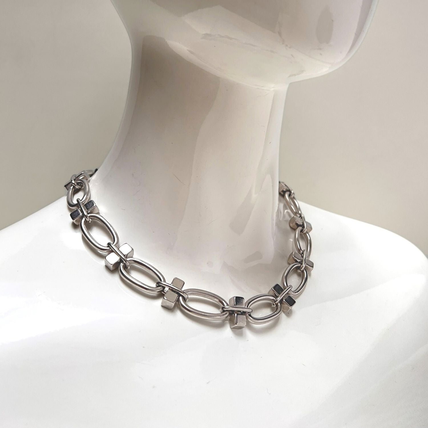 The Silver Reign Collier Necklace by JAREDJAMIN Jewelry Online features large oval links and small square connectors in silver-plated brass, forming a polished, reflective circle secured with a toggle clasp.