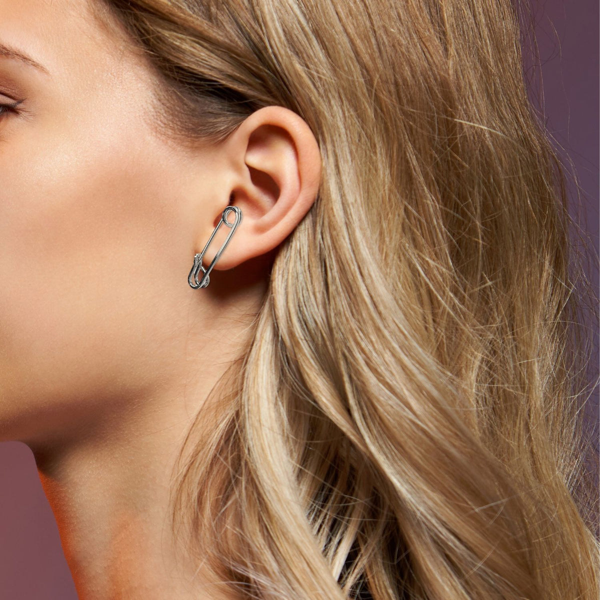 A クローズアップ of a woman's ear wearing JAREDJAMIN ジュエリーオンライン's シルバー Safety First Post イヤリング 付きの punk-inspired designとsurgical steel post.