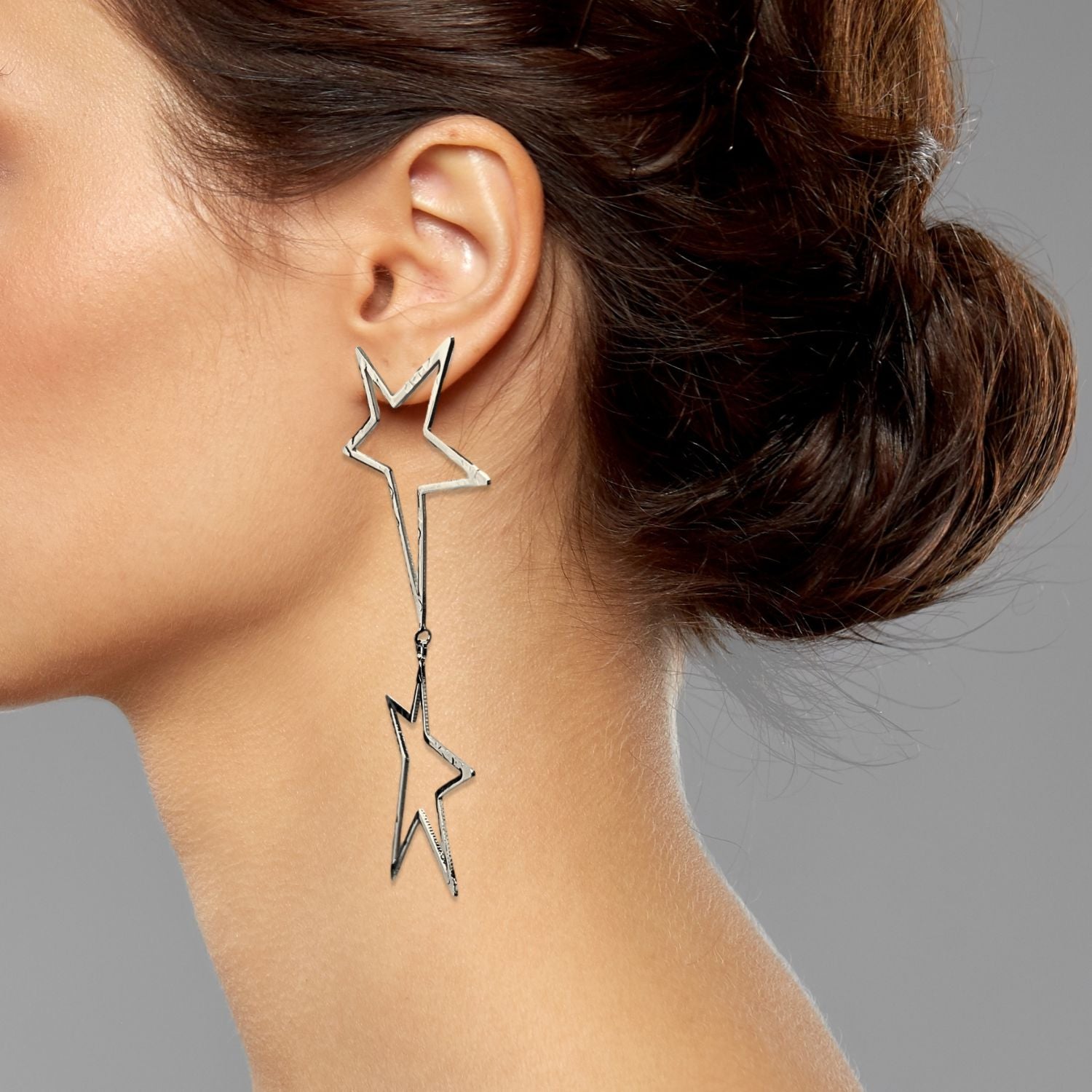 The Silver Shooting Star Dust Dangle Post Earrings by JAREDJAMIN Jewelry Online feature two open star outlines in a vertical line with a hammered finish, adding modern geometric flair to their shiny silver look.