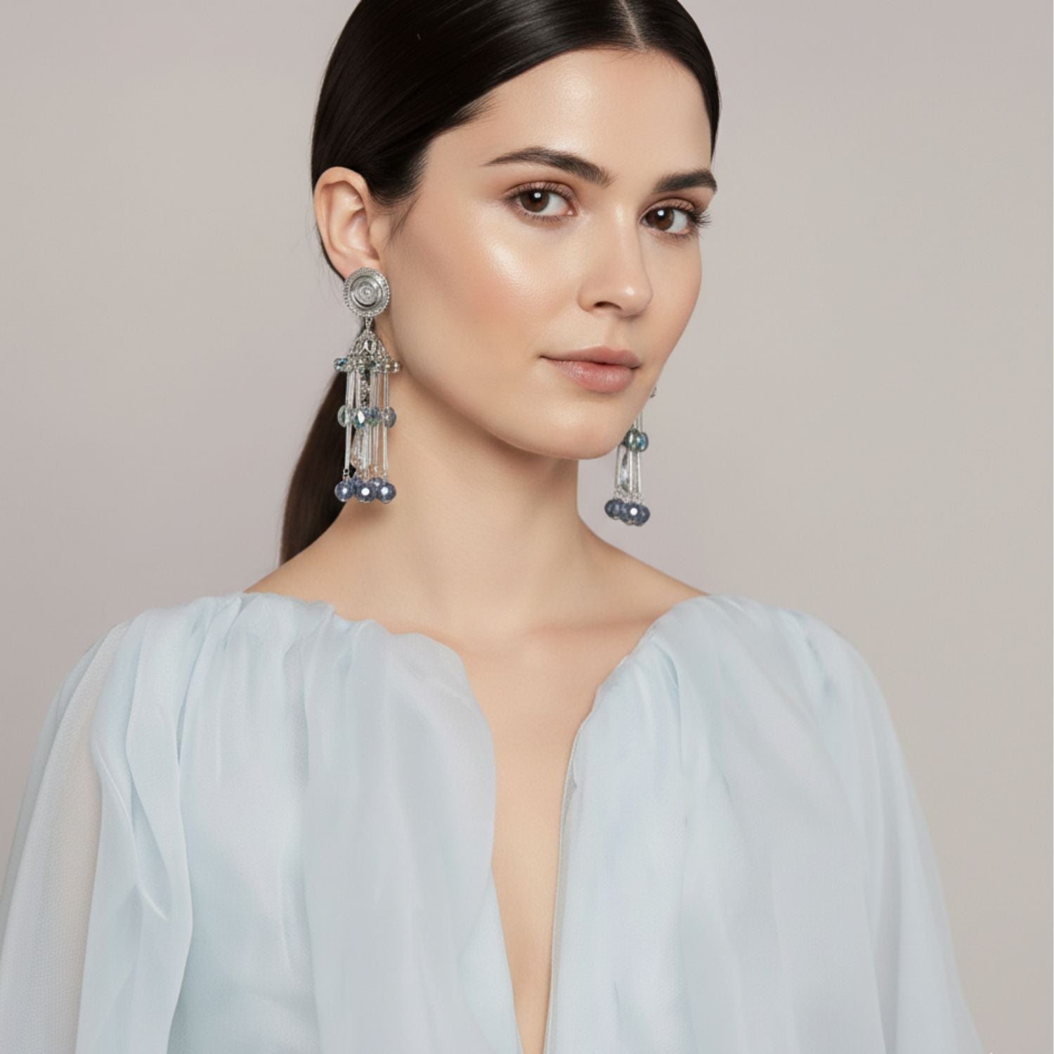 The Sixties Solar Sister Clip On Earrings by JAREDJAMIN Jewelry Online feature silver-tone chandeliers with circular studs, cascading iridescent crystals, faceted light blue beads, and silver plated components for a chic tiered look.