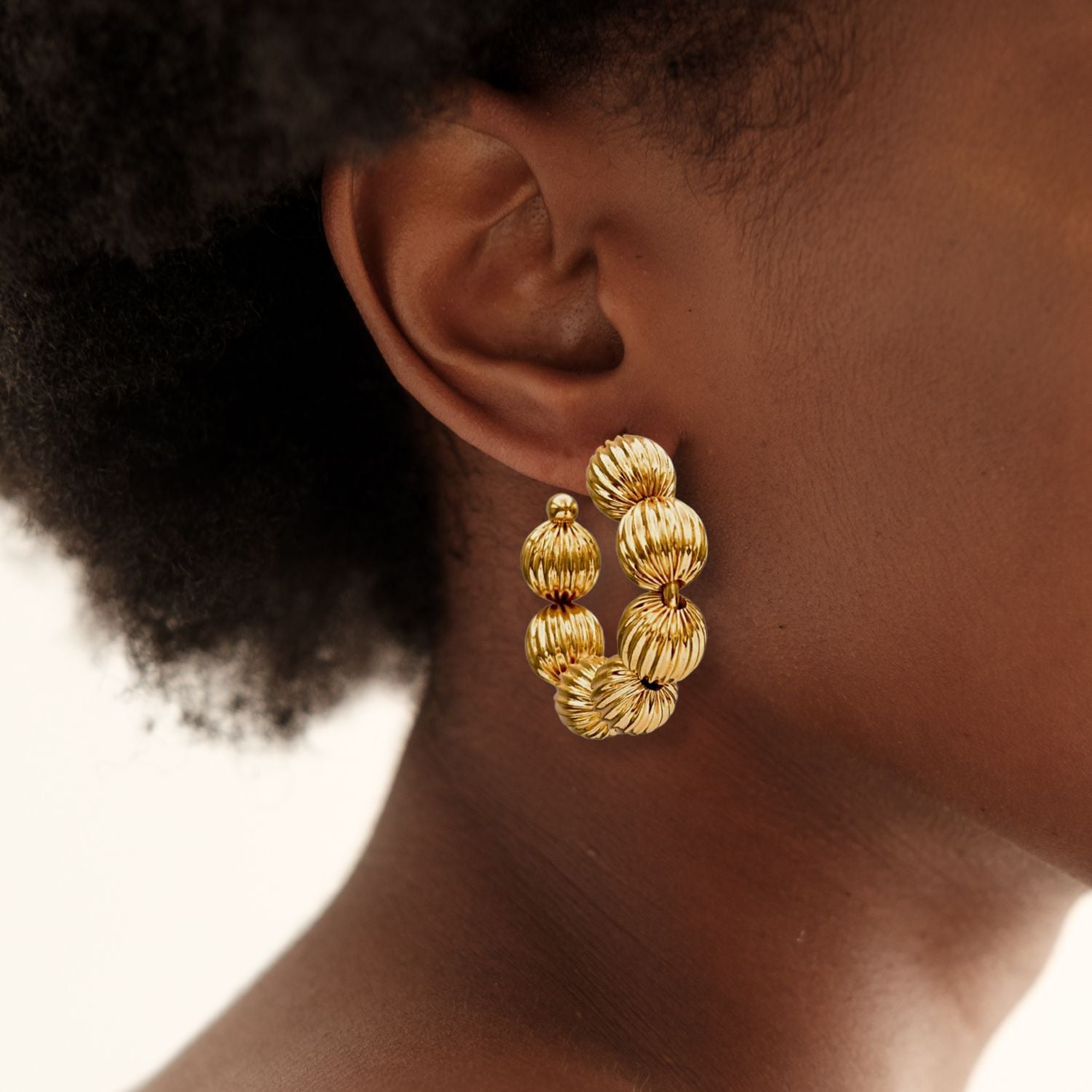 The Small Gold Lantern Hoop Post Earrings by JAREDJAMIN Jewelry Online are 18k gold plated with ribbed, round beads in a semi-circular design. Lightweight and stylish, these hoops are shown on a white background.