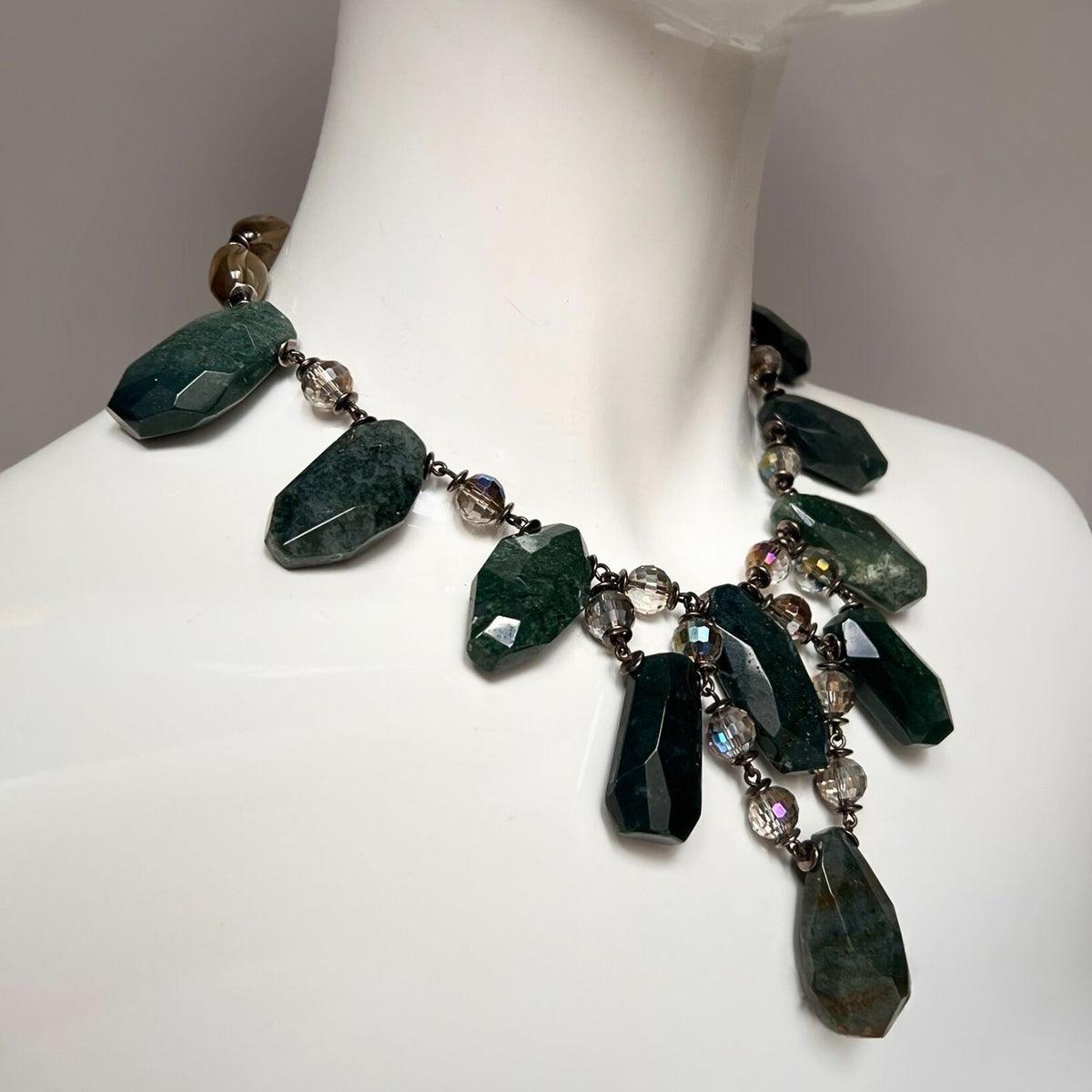 Close-up of the JAREDJAMIN Versailles Vixen Jasper Necklace on a mannequin bust, showcasing large, faceted green stones interspersed with round, iridescent beads for a cascading effect. The adjustable length and rich green shades make it perfect for pairing with Smoky Quartz beads.