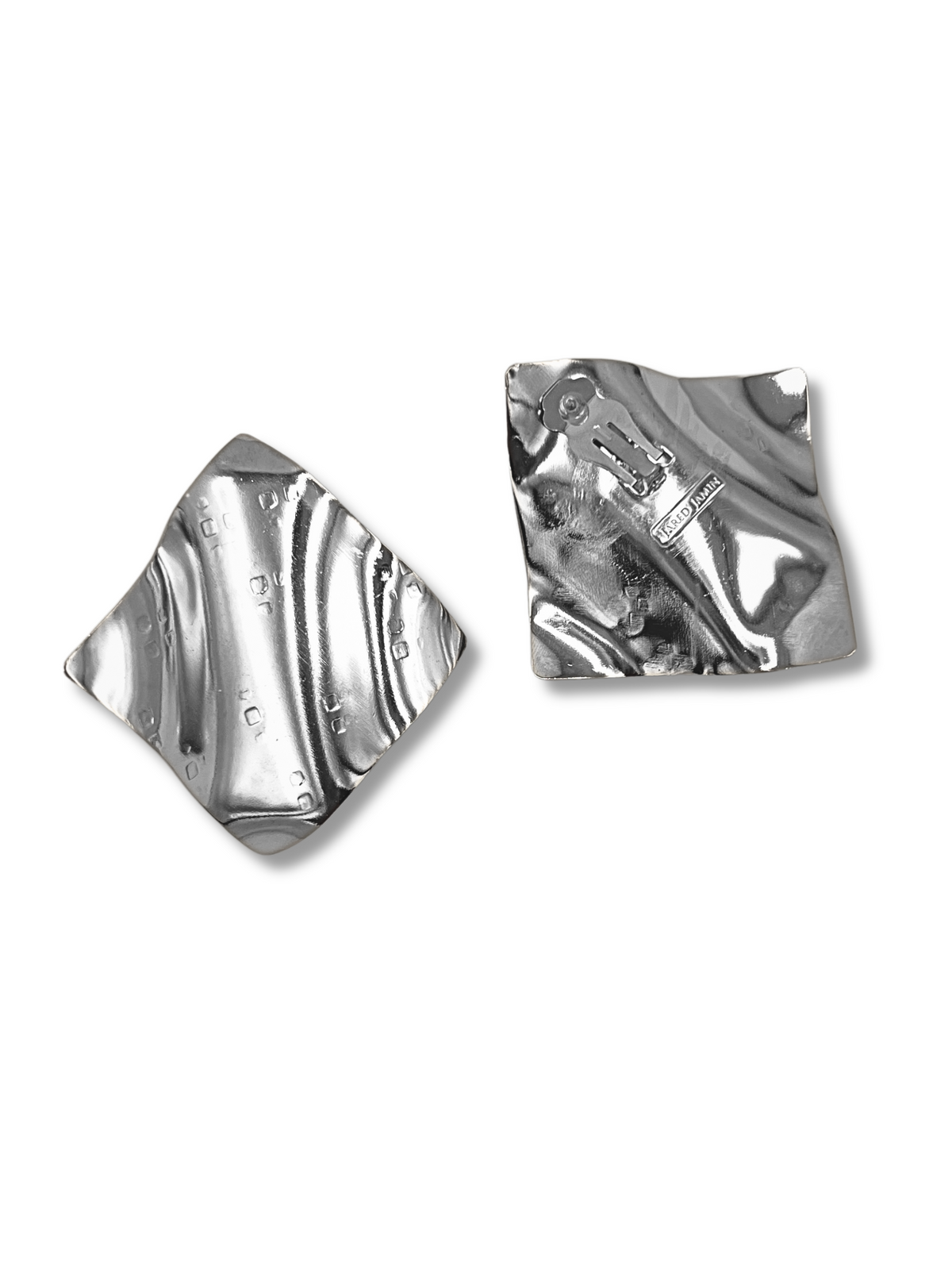 Two irregularly shaped polished silver squares rest on a white background. The left has small circular indentations, while the right gleams like Whitney Wave Earrings from JAREDJAMIN Jewelry Online, displaying a shiny surface with subtle texture variations.