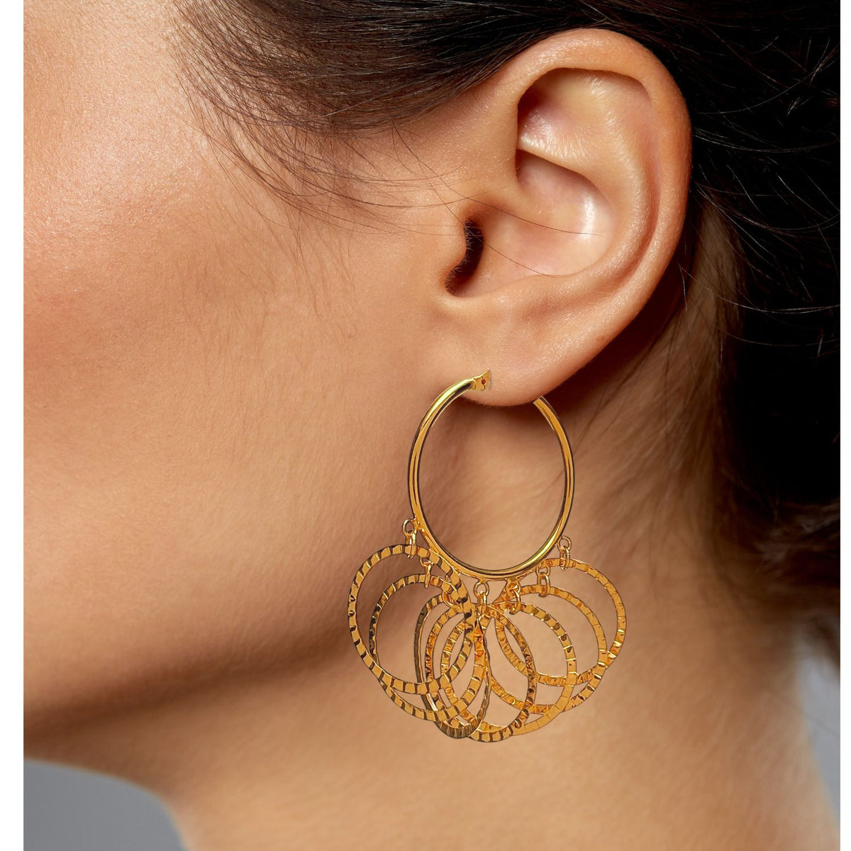gros plan of a woman's ear wearing Zephyr créole Click-Top boucles d'oreilles par JAREDJAMIN Bijoux en Ligne. Les 18K or créoles présentent multiple pendante bagues, a brillant finish, et intricate design, set against a neutral gray background.