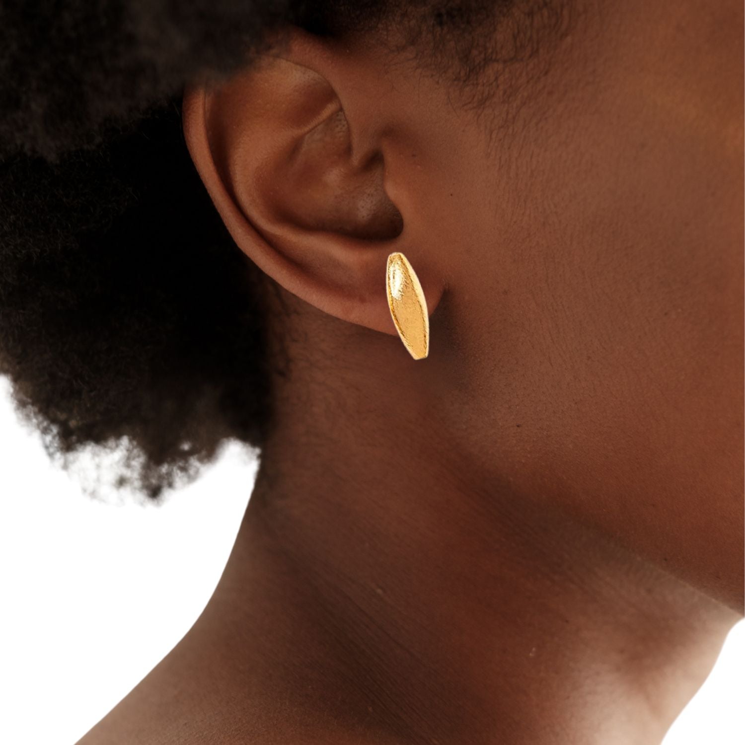 The Zeppelin Gold Stud Post Earrings from JAREDJAMIN Jewelry Online feature 18K goldplating, an oval domed shape, and a brush-textured matte finish. Shown diagonally on a white background with soft shadows.