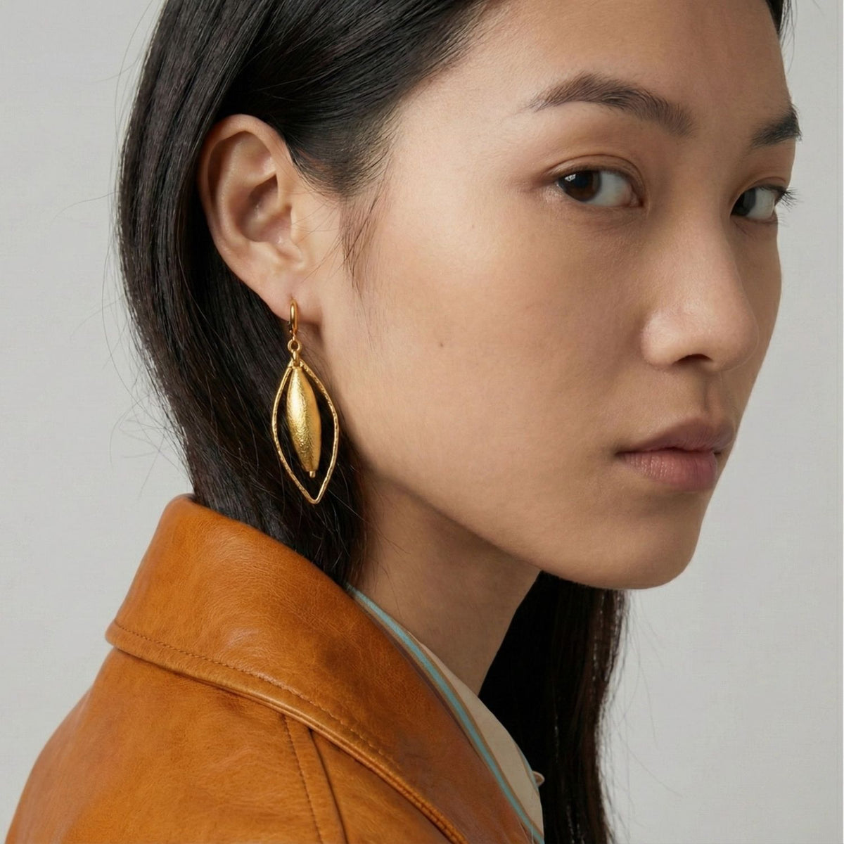 Zeppelin Haley oro Leverback pendientes, Medium de JAREDJAMIN Joyería Online shine in radiant oro con a brushed finish. Crafted sustainably in small batches in West Hollywood, they exemplify artisanal de lujo y signature texture. Model wears brown leather jacket.