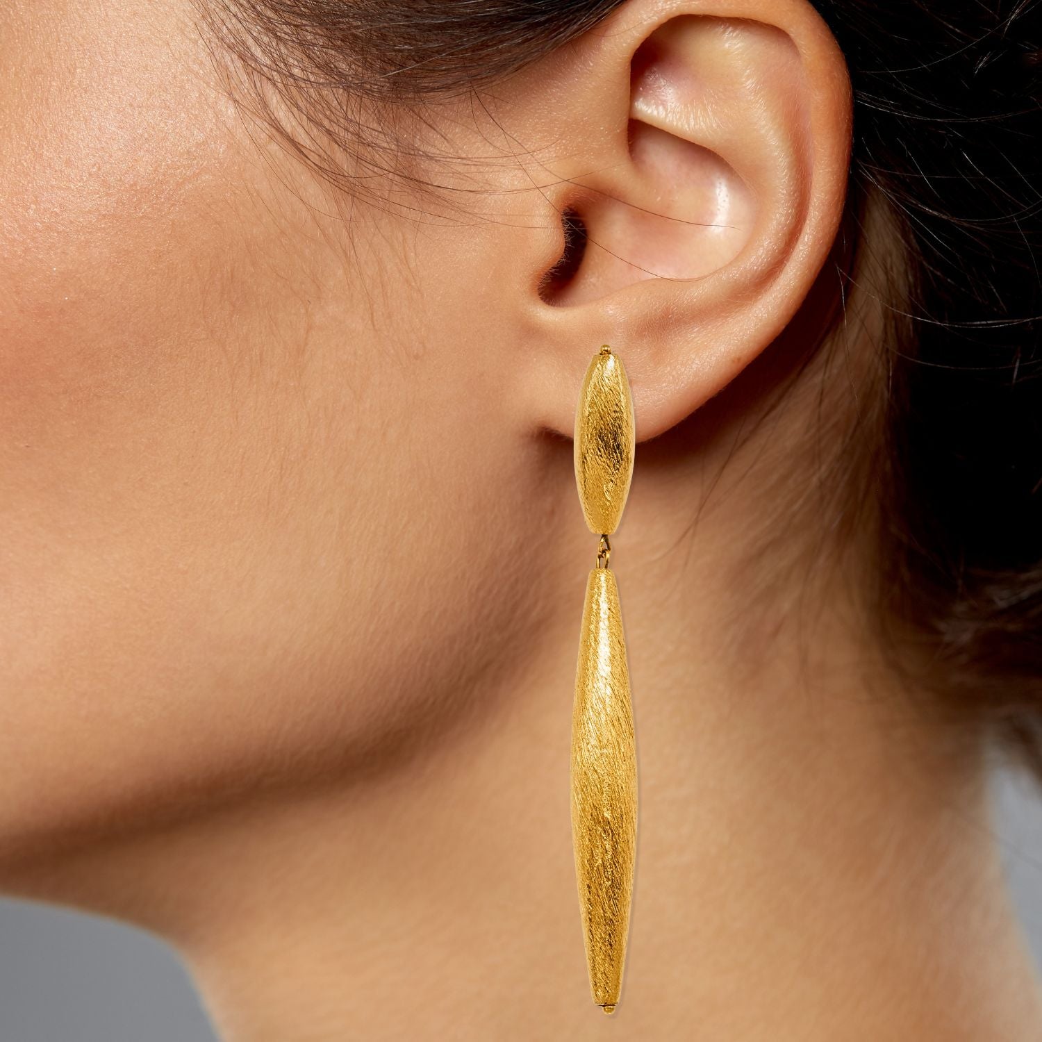 A pair of Zeppelin Isla Two Drop Gold Earrings by JAREDJAMIN Jewelry Online, featuring elongated gold drops with a brushed matte finish and rounded oval studs. The earrings are displayed against a white background.