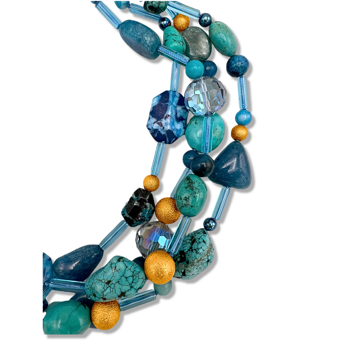 Un primer plano of the Blue Reef collar de JAREDJAMIN Joyería Online, a hand-knotted, multi-strand piece con assorted turquoise, blue, y 18K Stardust beads in various shapes, shown against a fondo blanco.