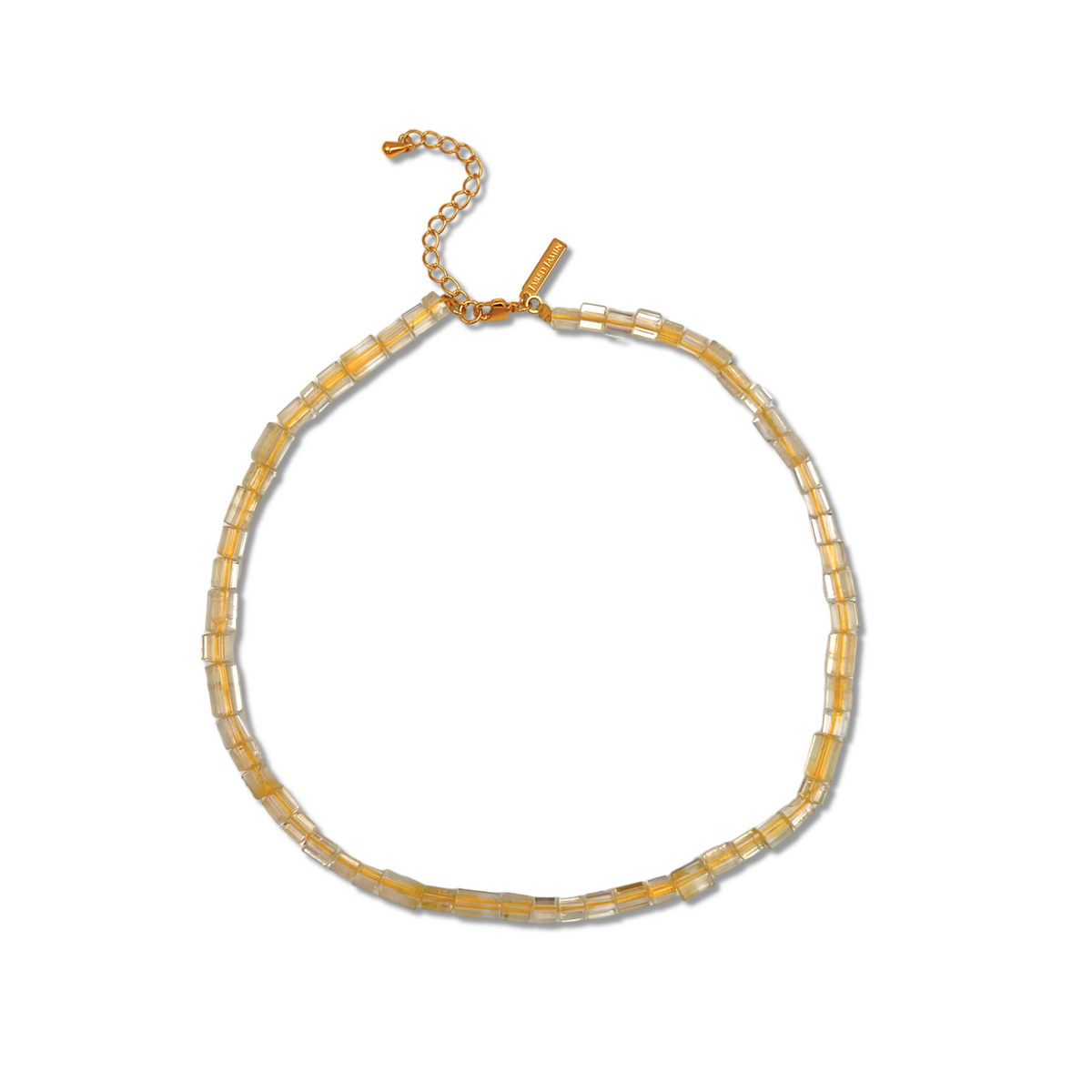 The Faceted Citrine Bead Necklace by JAREDJAMIN Jewelry Online features small translucent citrine and clear cylindrical beads in pale yellow, with a gold chain extender and rectangular tag, arranged circularly on a white background.