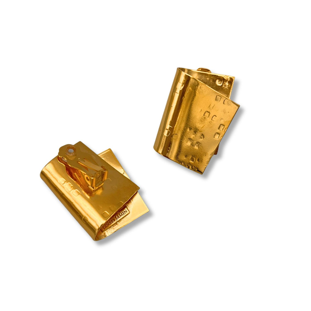 Two brillant or Fold Over Clip boucles d'oreilles par JAREDJAMIN Bijoux en Ligne rest sur un fond blanc. Each has a rectangular body avec sleek lines, echoing architectural design. One stands upright; the other lies flat, showing embossed text.