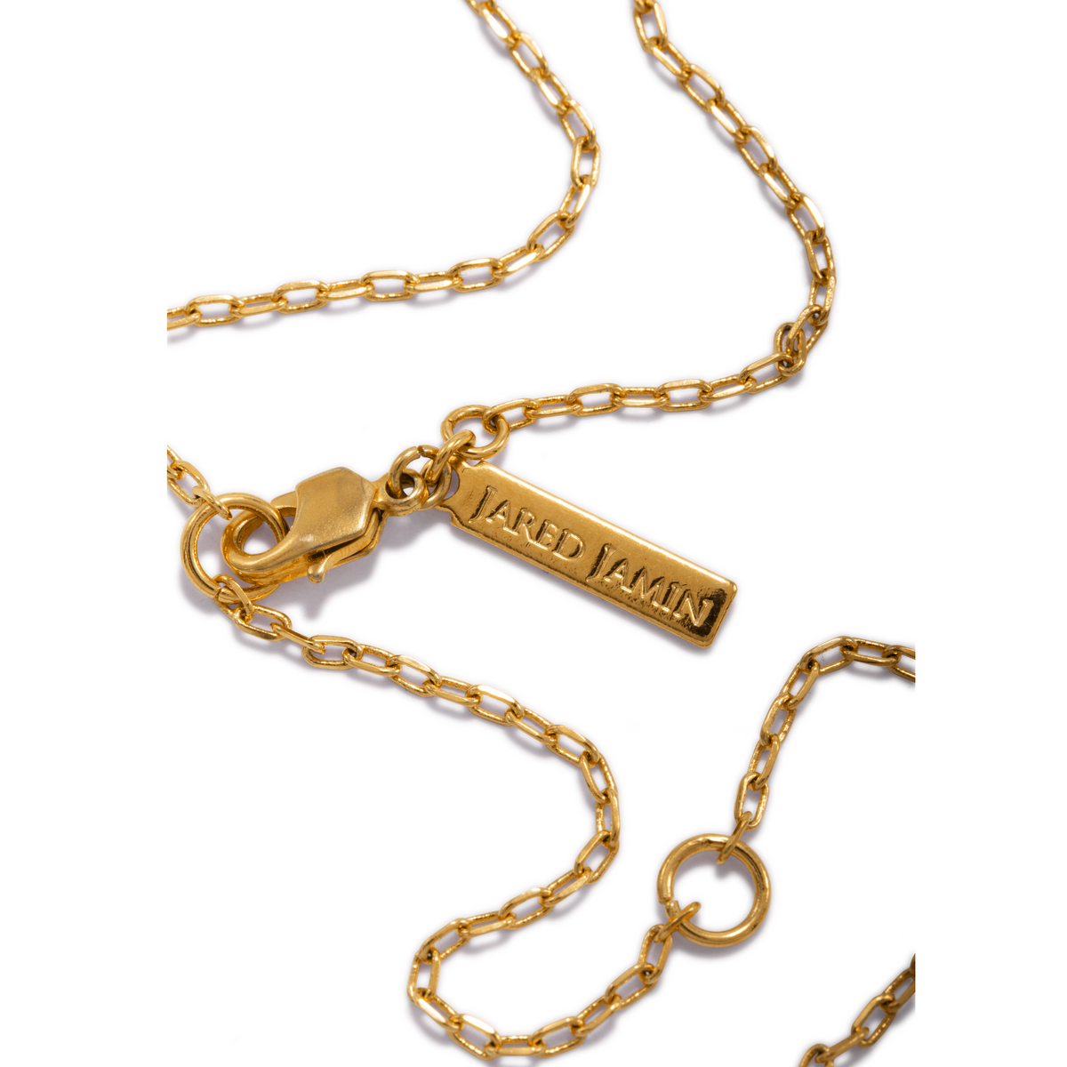 Close-up of the Gold Hammered Doughnut Pendant Necklace by JAREDJAMIN Jewelry Online, featuring a polished gold pendant on a chain with a lobster clasp and rectangular “JAREDJAMIN” tag, displayed against a white background.