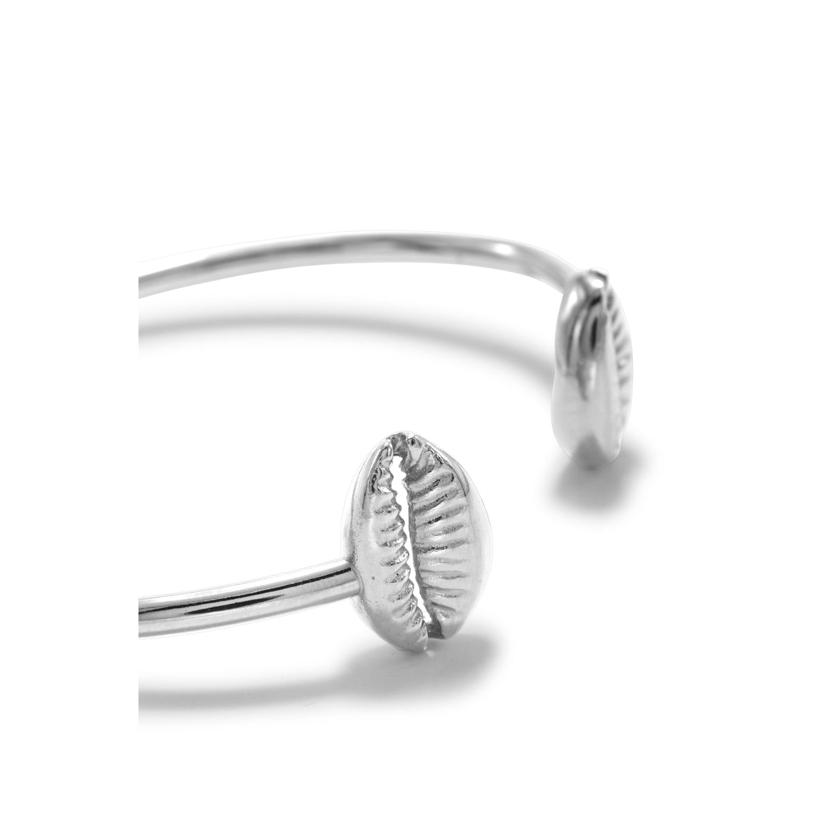 A クローズアップ of シルバー Cowrie Shell カフ ブレスレット JAREDJAMIN製 ジュエリーオンライン, 特徴とする two cowrie shell-shaped ends facing each other at open ends, shown against a plain 白い背景.