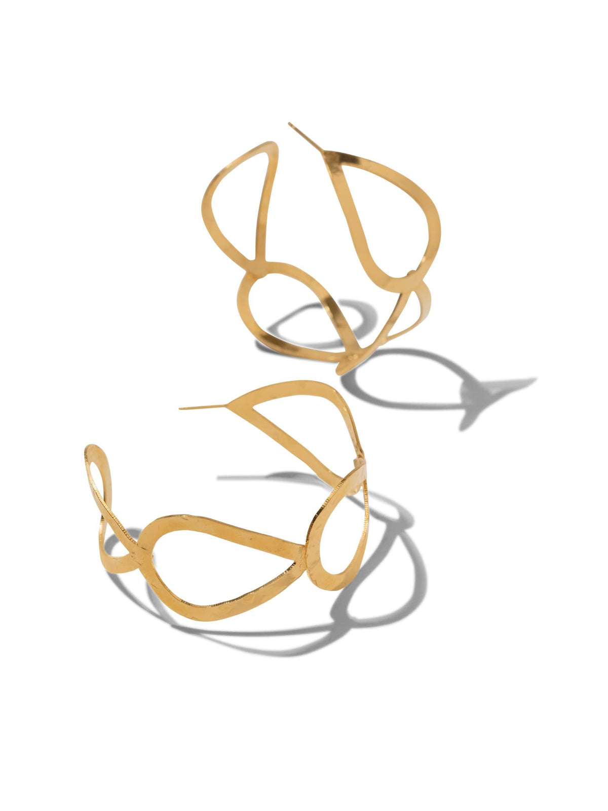 The Julia Hoop Post Earrings by JAREDJAMIN Jewelry Online feature tarnish-free 18K gold with open, fluid designs on a white backdrop. Their abstract curves create delicate shadows, highlighting their artistic and modern aesthetic while the metal&#39;s shine adds an elegant touch.