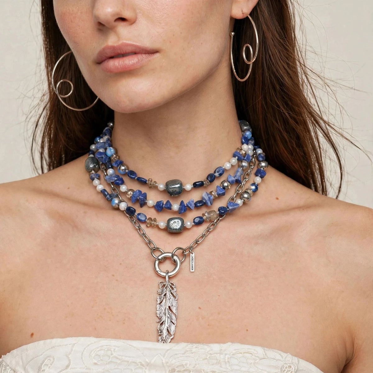 Lorelei Beaded Gemstone Necklace, model wearing the blue gemstone necklace layered with a silver feather pendant.