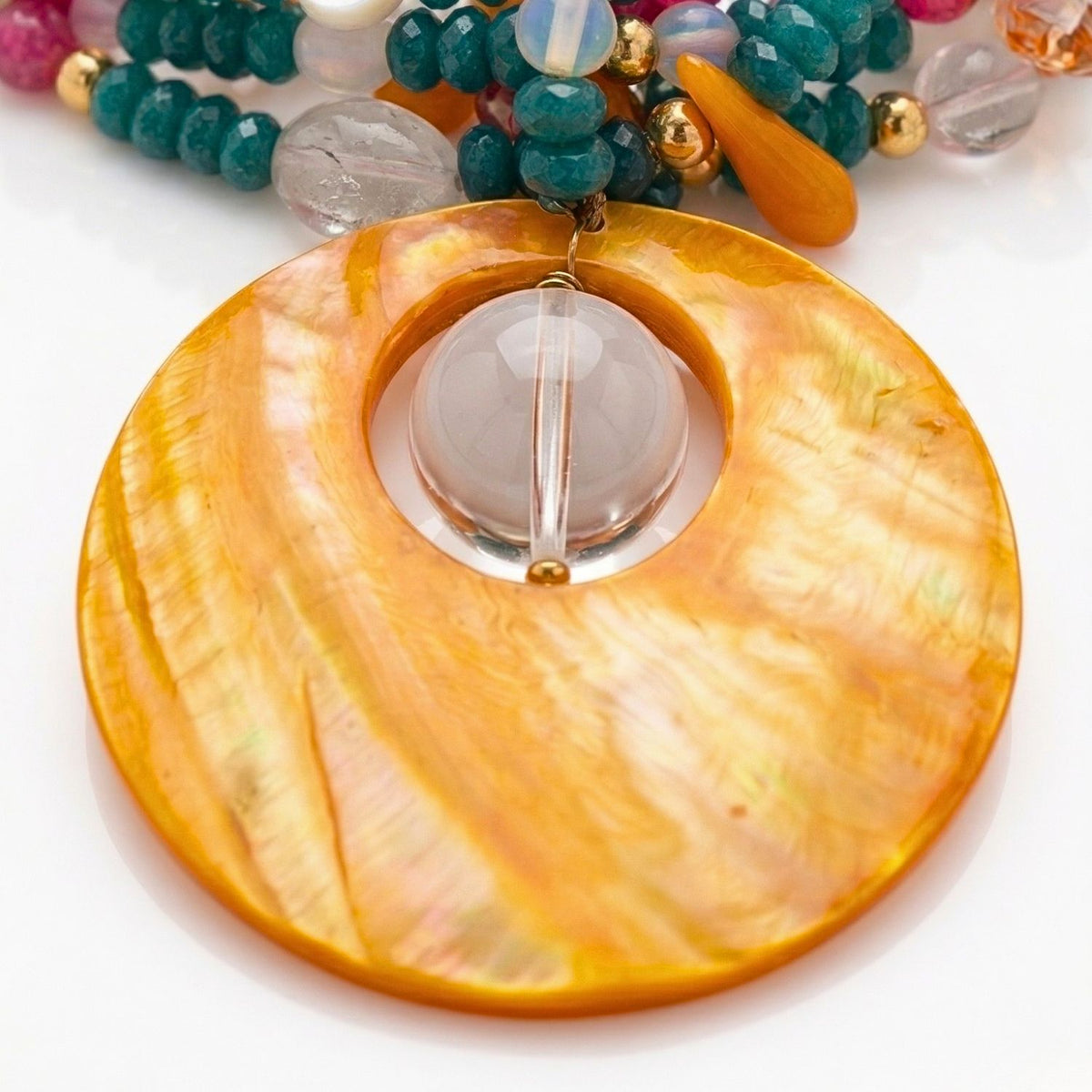 クローズアップ of Molly ネックレス ペンダント: a hand-selected orange mother-of-パール disc 付きの clear クリスタル クォーツ center, manually wroughtのためのan artisanal, one-of-a-kind finish.