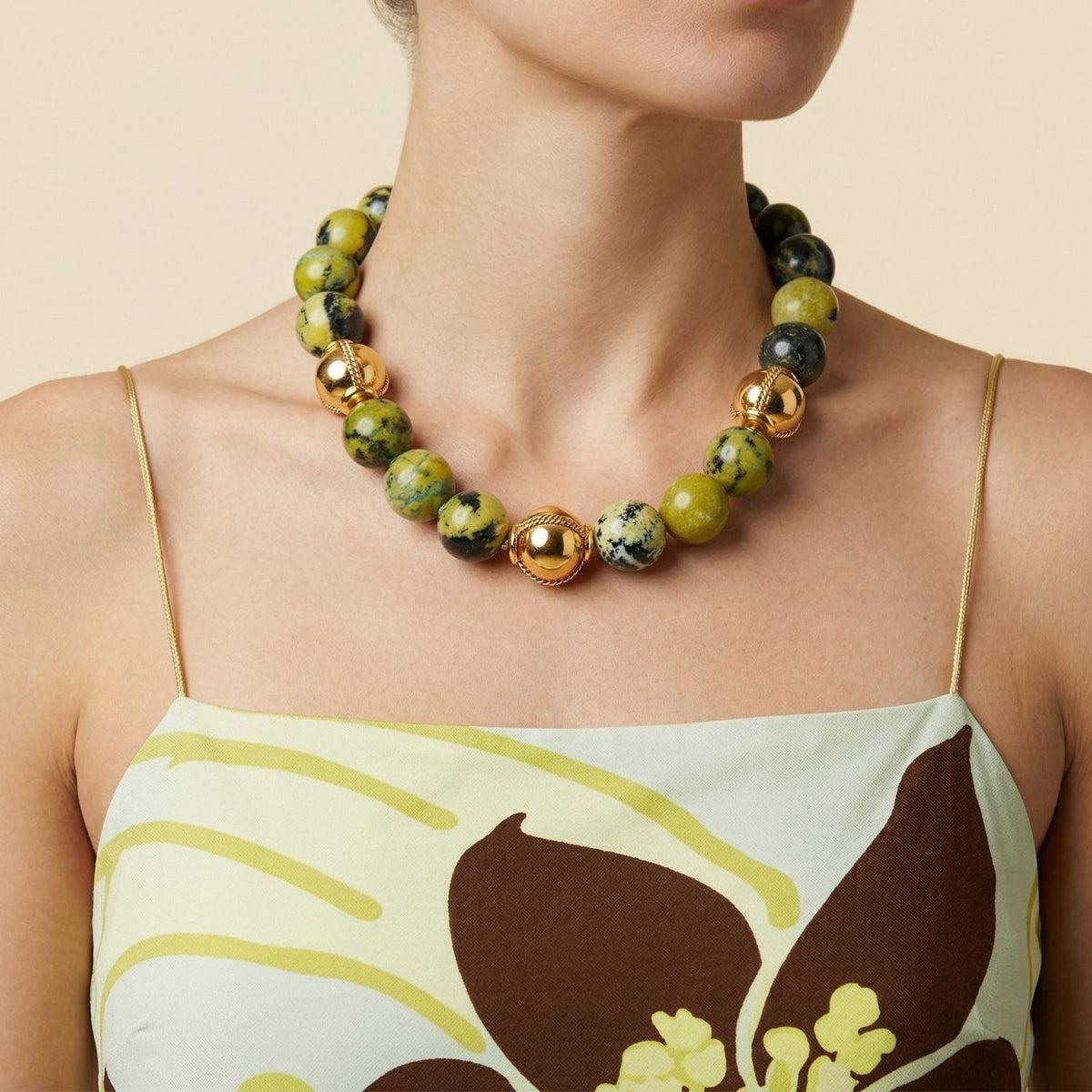 Moss Maiden Necklace by JAREDJAMIN: green moss agate beads and large gold-plated accents, brushed finish. Artisanal craftsmanship small-batch, West Hollywood, sustainable luxury low carbon footprint, signature texture. Worn with a floral dress.