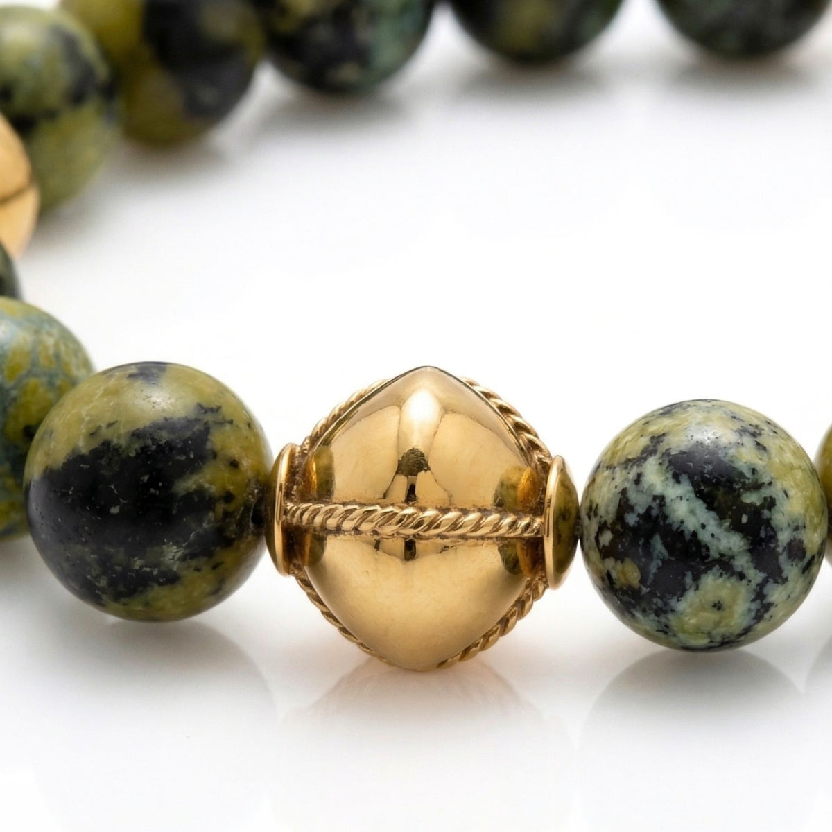 The Moss Maiden Necklace showcases round green and black speckled stone beads paired with a brushed 18K gold-plated geometric centerpiece. Handcrafted in West Hollywood, this JAREDJAMIN Essential offers sustainable luxury and signature artisanal texture.