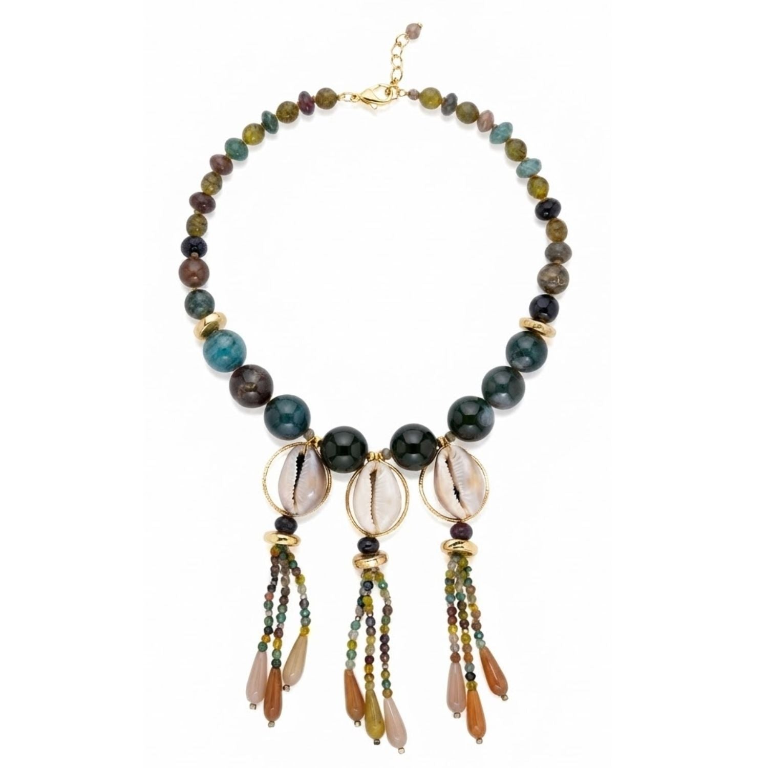 A statement necklace laid in a circle on a white background: small faceted dragon vein agate beads in translucent olive and mossy greens graduate into large polished deep-green jasper rounds with natural veining; three natural cowrie shells, creamy ivory with brown markings, hang at the center front, each framed in a gold-tone textured circular link; below each shell a beaded dangle ends in honey-amber teardrop pendants; a gold-tone lobster clasp with extender chain at the top.