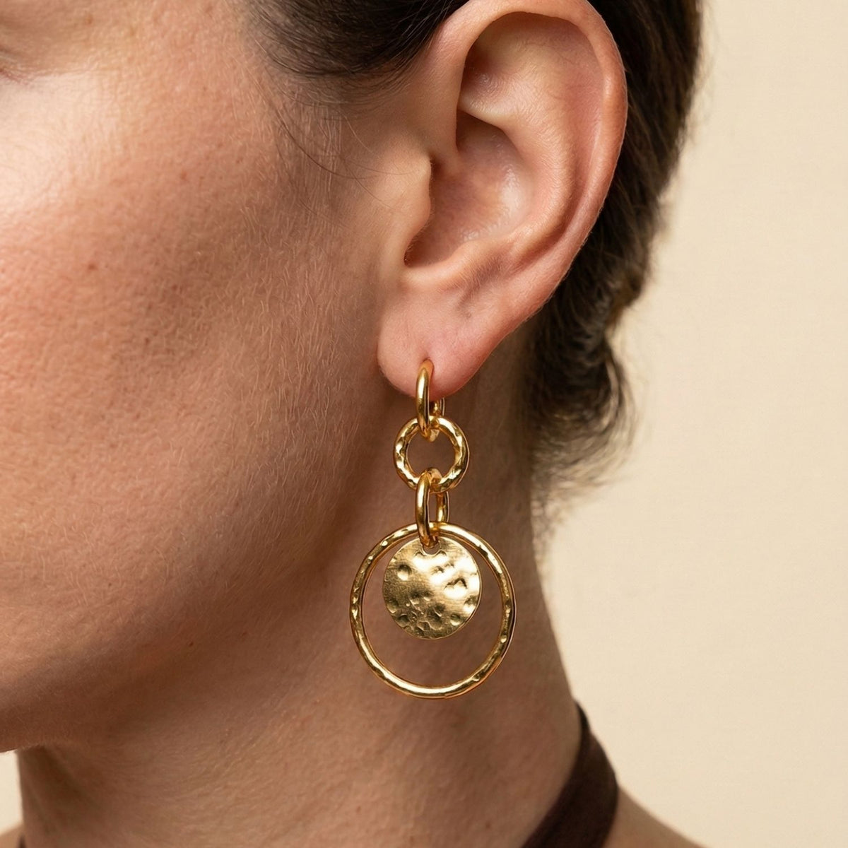 Close-up of Peacock Preen Clip-On Earrings by JAREDJAMIN Jewelry Online—18K gold plated with textured circular stud, hammered hoops, and disc. JAREDJAMIN Essential: Artisanal Craftsmanship West Hollywood, Sustainable Luxury, Signature Texture.