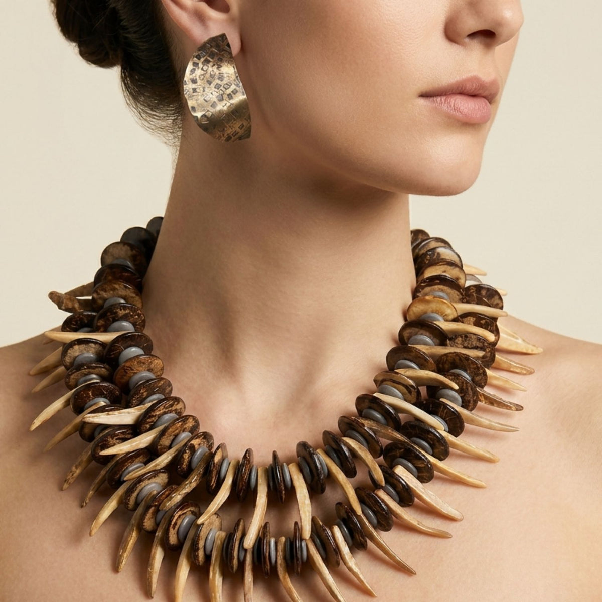 Close-up side profile portrait of a model wearing the JAREDJAMIN Pergola Perfection One-of-a-Kind Double-Strand Organic Necklace against a neutral background, highlighting the layered coconut discs, hematite spacers, and projecting wooden spike beads.
