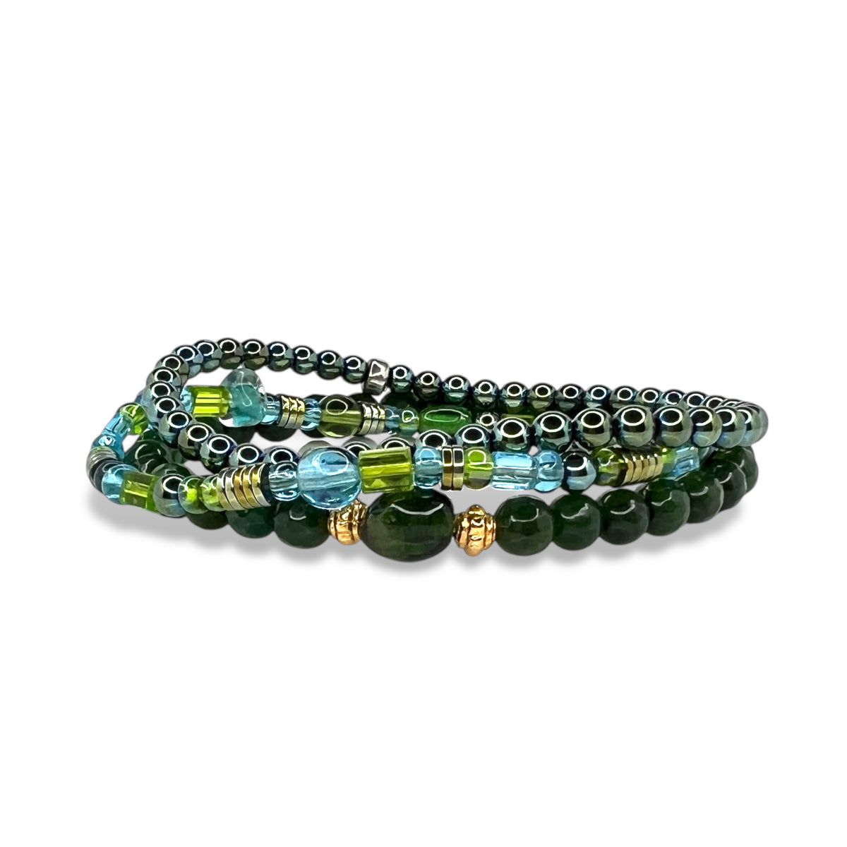 The Emerald City Bracelet Set by JAREDJAMIN Jewelry Online features multiple strands with green, blue, and silver beads—aventurine, abalone shell, glass, metallic accents—and gold-toned hematite spacers for added shine. Displayed on a white background.