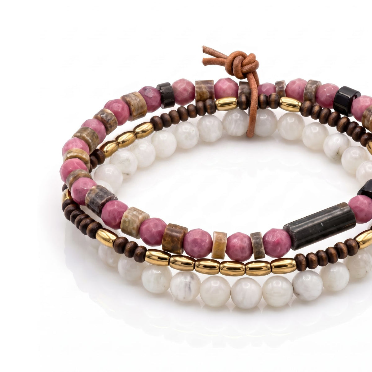 High-resolution studio product shot of the Cassian 3-piece stretch bracelet set lying flat, showing the detailed contrast between the faceted pink jasper, smooth quartz, and tiny wood rondelles.