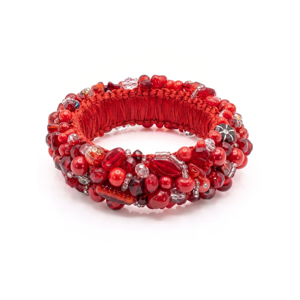Angled studio layflat shot of the JAREDJAMIN Pomegranate Princess Bangle resting on a white surface, showcasing the inner satin ribbon wrapping and the structural 1-inch width of the hand-embroidered bracelet.