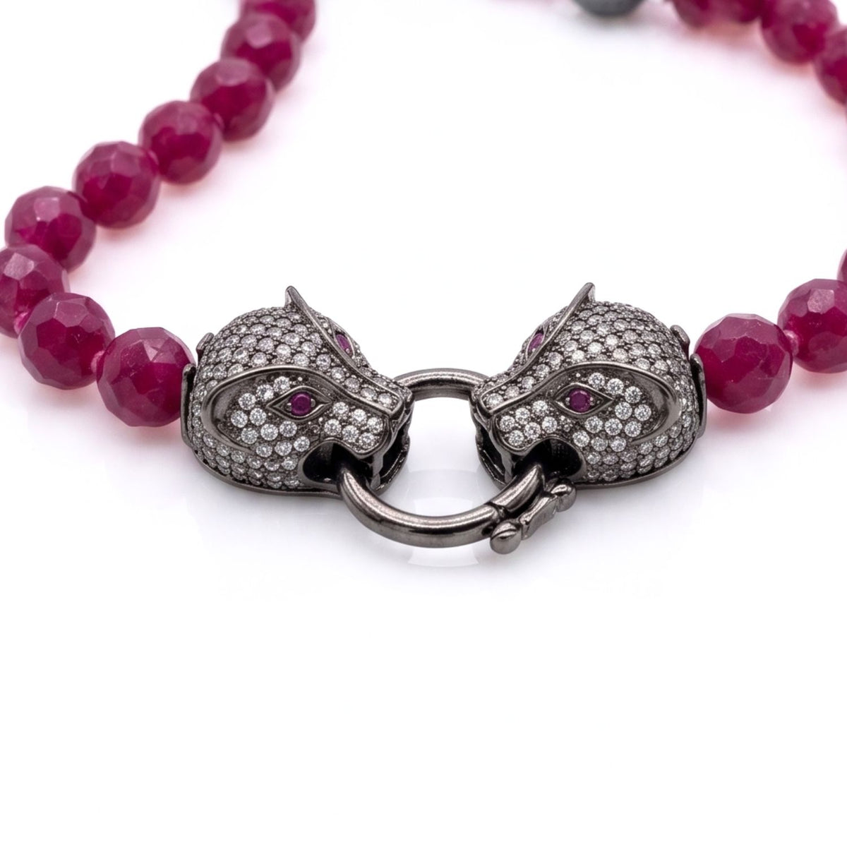 Macro studio shot of the black rhodium-finished panther motif pavé clasp securely fastened, detailing the fine hand-set quality of the cubic zirconia crystals against the raspberry beads.