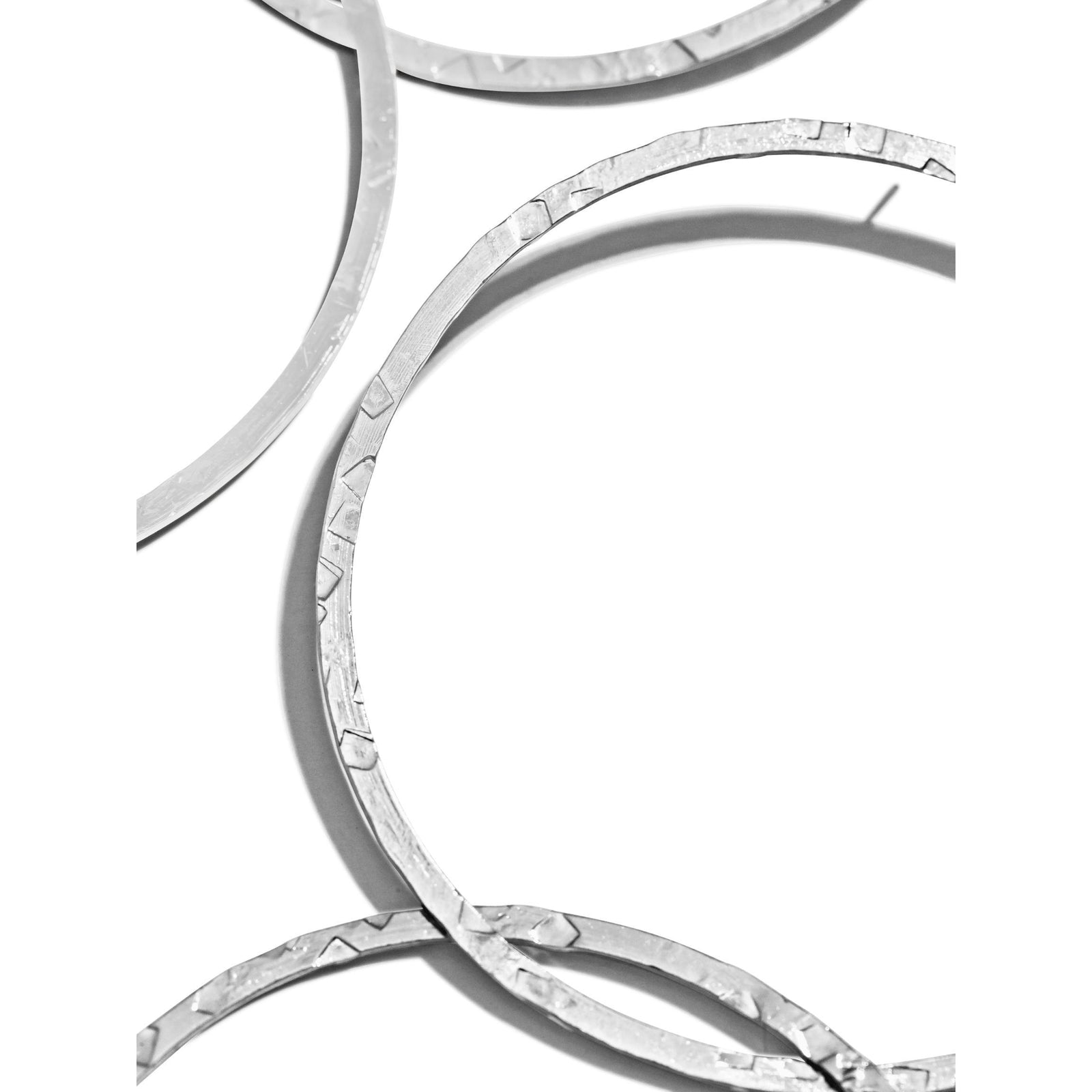 Three pairs of Silver Raquel Dangle Hoop Post Earrings by JAREDJAMIN Jewelry Online are displayed on a white background. The intertwined hoops feature a hammered, faceted silver plate finish for added texture and shine.