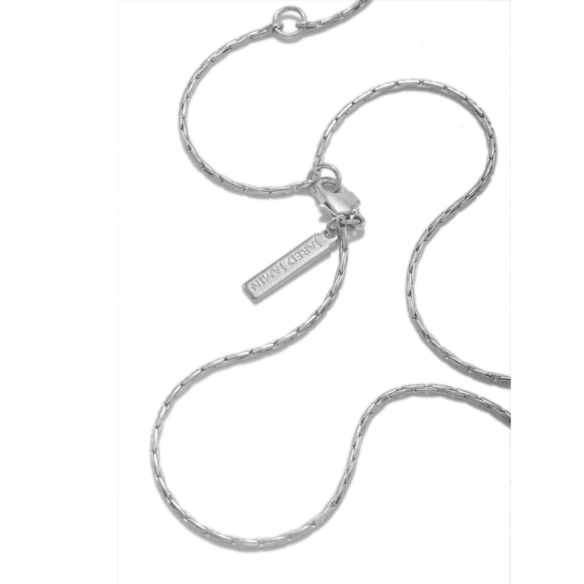 Los Ricky Adjustable cadena collar de JAREDJAMIN Joyería Online is a delicado plata piece con a snake cadena y lobster clasp, con a small "JAREDJAMIN" tag. Los cadena is displayed in gentle curves sobre un plain fondo blanco.