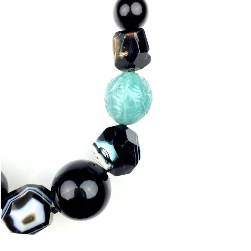 Los Rock Of Gibraltar collar de JAREDJAMIN Joyería Online features glossy black beads, vintage resin beads, a dyed faceted agate con white y gray swirls, an aqua blue carved bead, y a faceted dark bead sobre un plain fondo blanco.