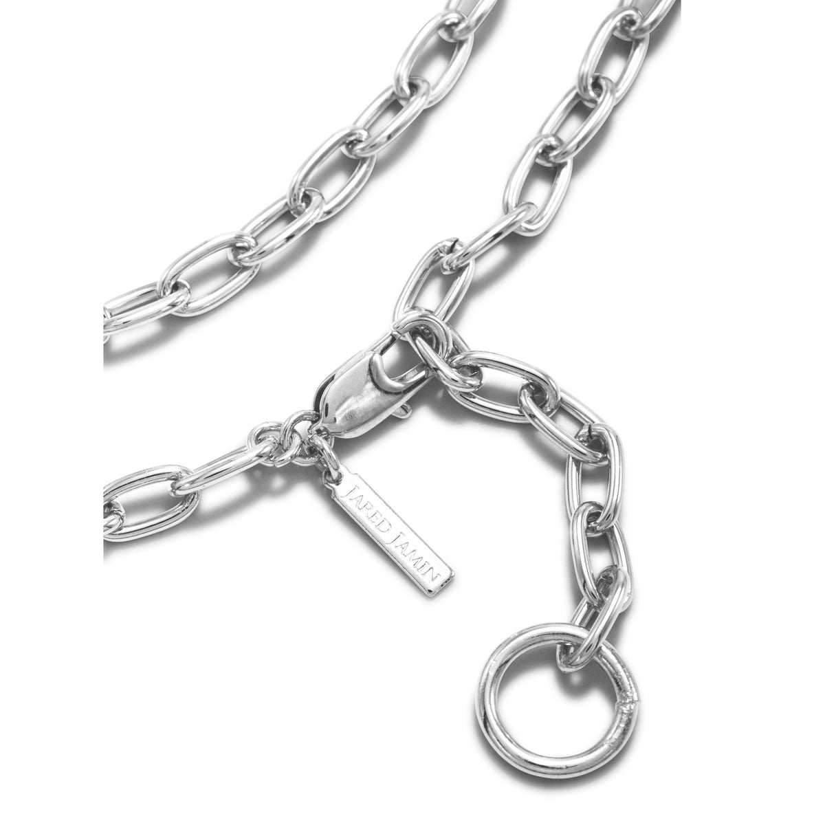 A クローズアップ of シルバー チェーン Reaction ネックレス JAREDJAMIN製 ジュエリーオンライン, 特徴とする オーバル links, a lobster clasp, a ラウンド リング,とa "JARED JAMIN" tag, arranged の上の 白い背景.