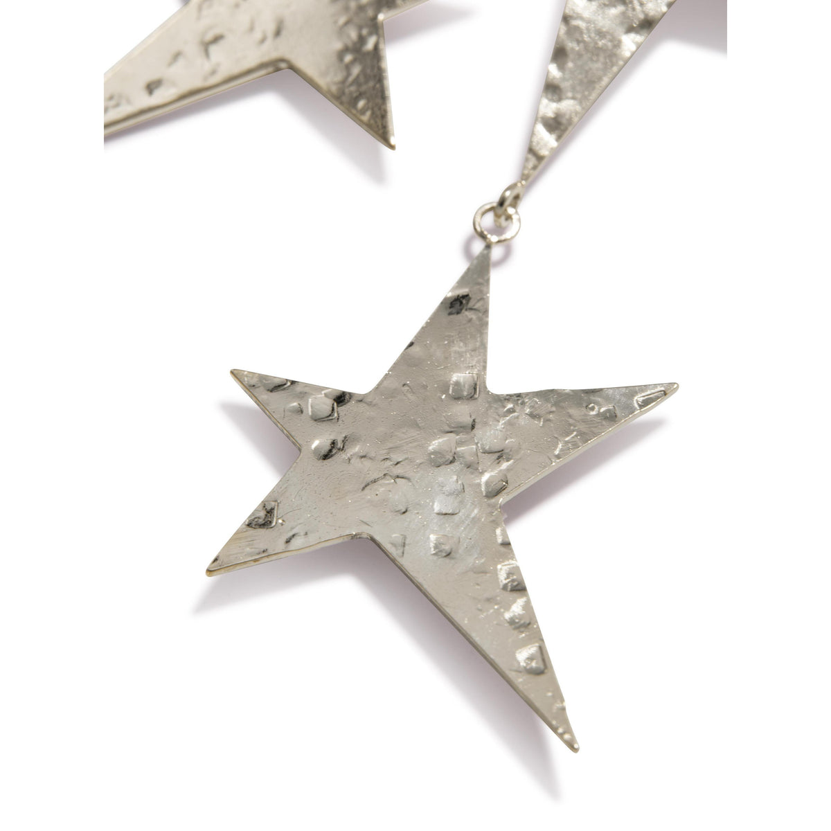 primer plano of JAREDJAMIN Joyería Online’s plata Shooting Star Dangle Clip On pendientes, con a brillante hammered finish, star shape, rough uneven surface, y joined by a small loop sobre un fondo blanco.