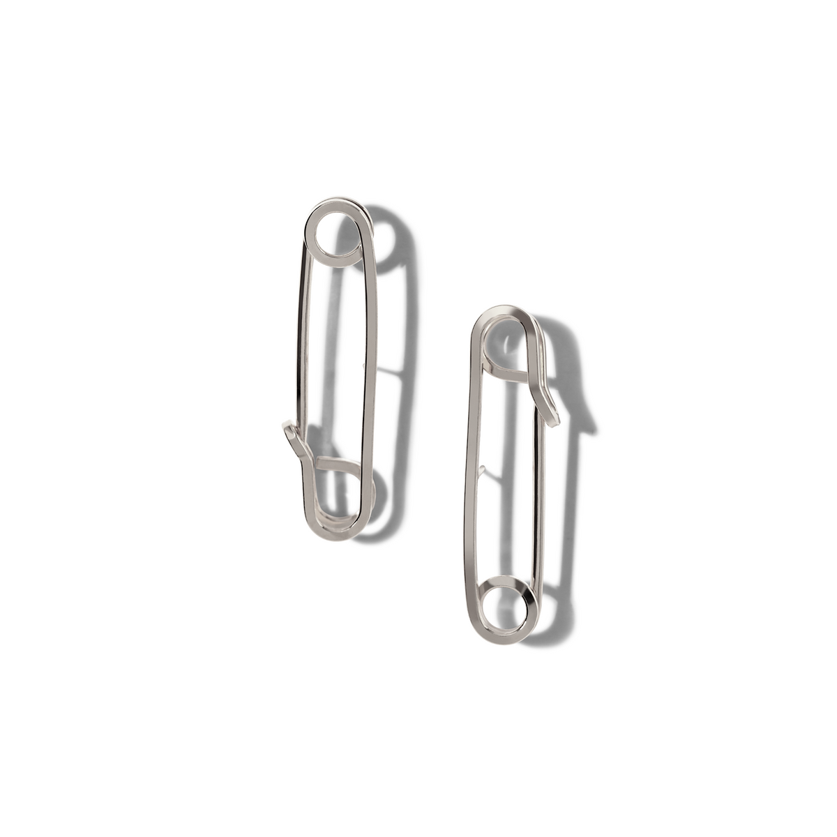 Two シルバー Safety First Post イヤリング JAREDJAMINの ジュエリーオンライン, crafted from surgical steel, are displayed vertically の上の 白い背景. Both イヤリング are closed, their 光沢のある surfaces reflecting a subtle punk vibe.