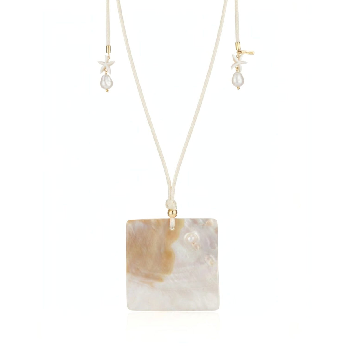 Macro close-up shot of the Maris square natural shell pendant, highlighting its organic pearlescent texture, gold-plated wire bail, and white howlite star cord ends.
