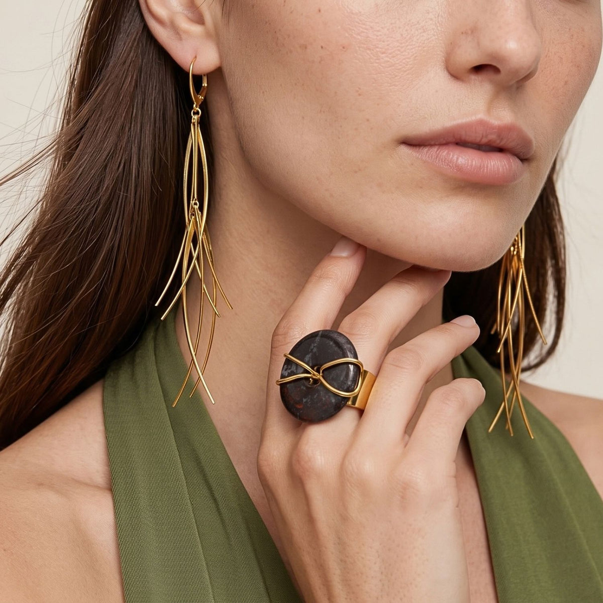 Gold Cornelia Ring, close-up of the dark stone cocktail ring with gold wire wrap, worn with tinsel drop earrings.