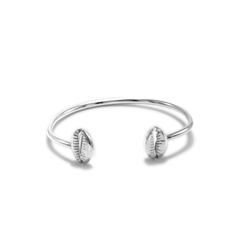 JAREDJAMIN ジュエリーオンライン シルバー Cowrie Shell カフ ブレスレット 特徴とする two detailed cowrie shell ends の上の ミニマリスト シルバー band, displayed against a plain 白い背景.