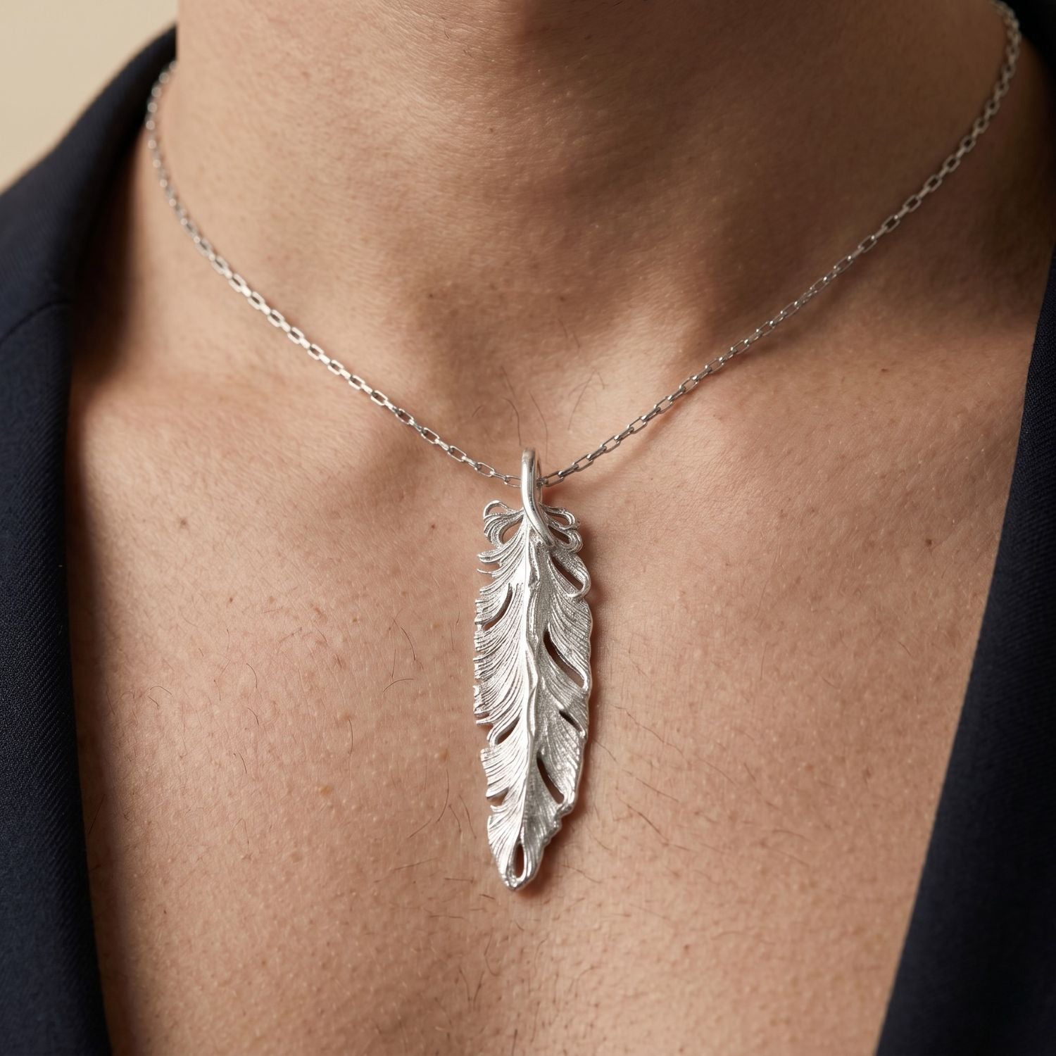 The Silver Plume Pendant Charm by JAREDJAMIN Jewelry Online features detailed textured lines, intricate cutouts, and a curved form, giving this white rhodium feather pendant a realistic look, complete with a small loop for easy attachment.