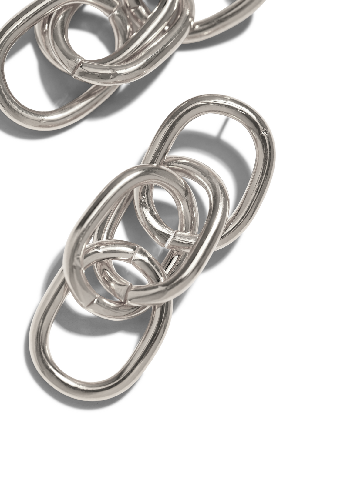 gros plan of argent Billie pendante Post boucles d'oreilles par JAREDJAMIN Bijoux en Ligne sur un fond blanc. Interlocking oval links cast soft shadows, highlighting their poli finish et élégant, curved design. Two boucle d'oreille sections are visible.