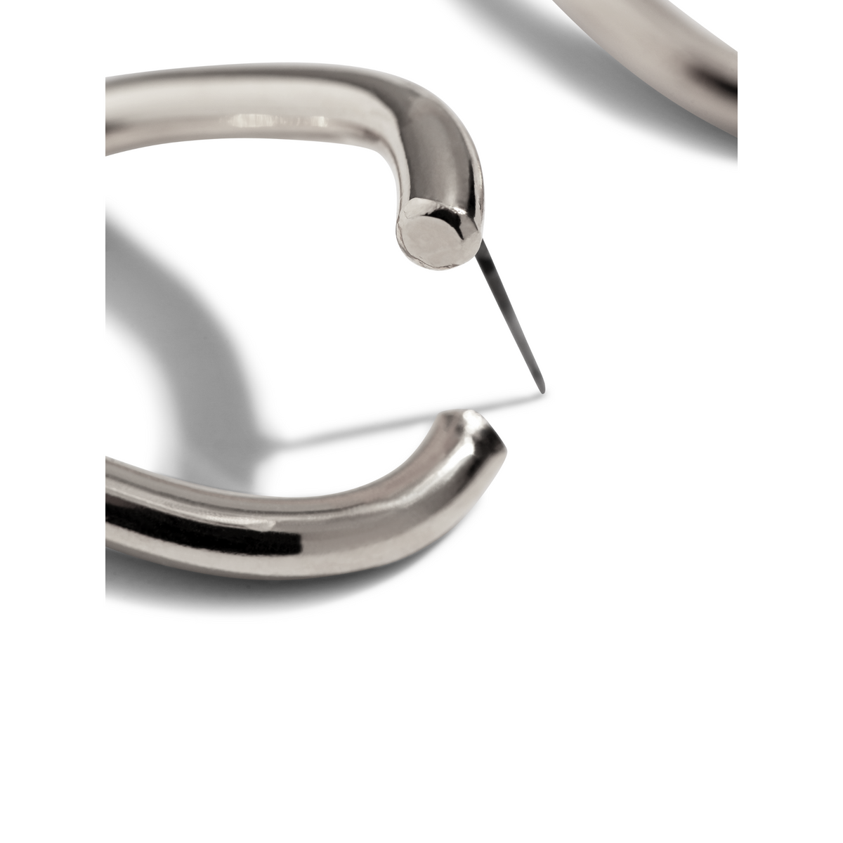 Un primer plano of a nail con edgy joyería y the plata Billie pendiente de botón Post pendientes de JAREDJAMIN Joyería Online spotlights modern style.