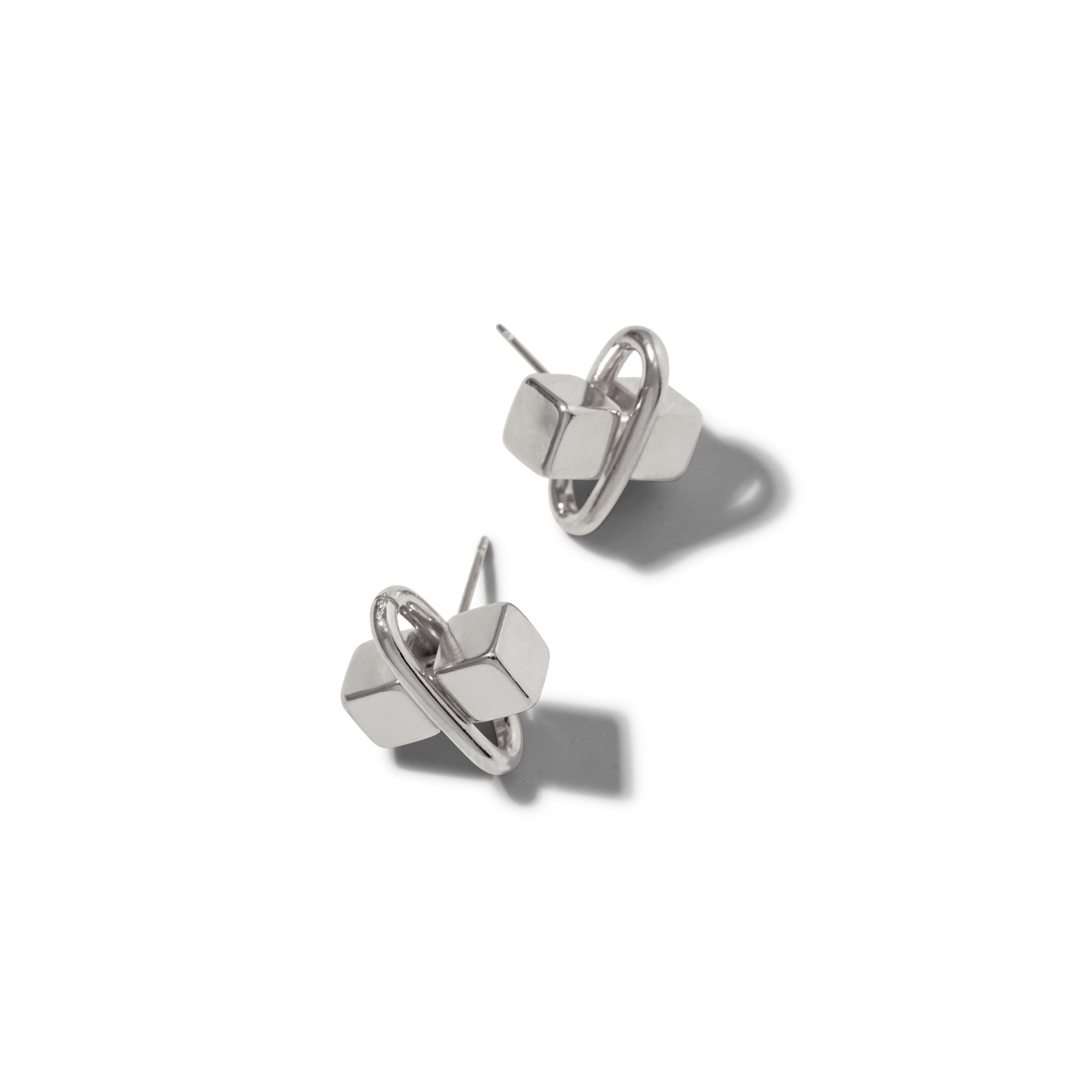 The Silver Blockbuster Stud Post Earrings by JAREDJAMIN Jewelry Online feature a modern geometric design with silver-plated brass bars intersected by rounded loops, their shiny surfaces and unique shapes highlighted against a white background.