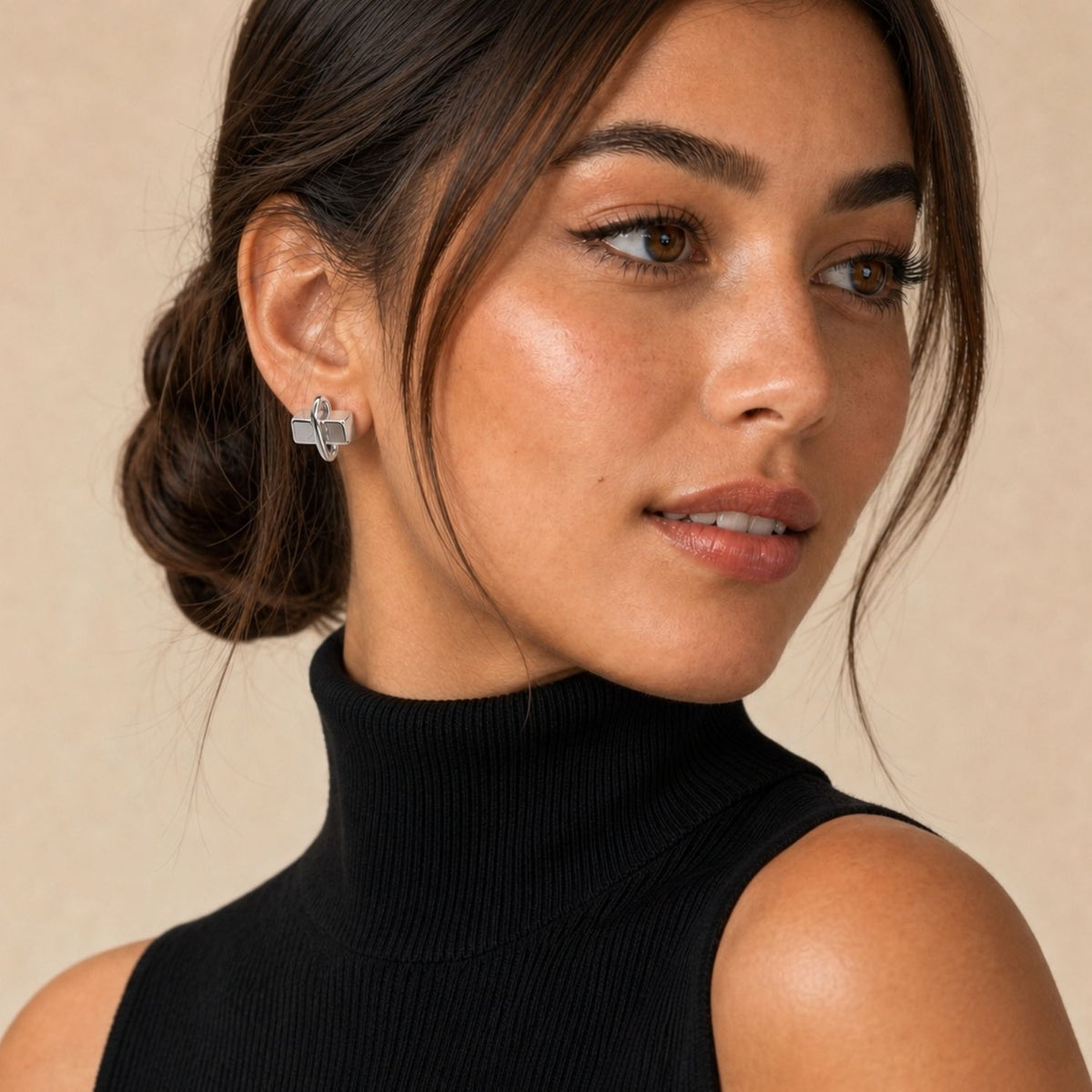 Close-up profile of a model styling the geometric Silver Blockbuster Studs, demonstrating how the icy, machined-metal cube design sits flush against the earlobe while physically popping out in three dimensions.